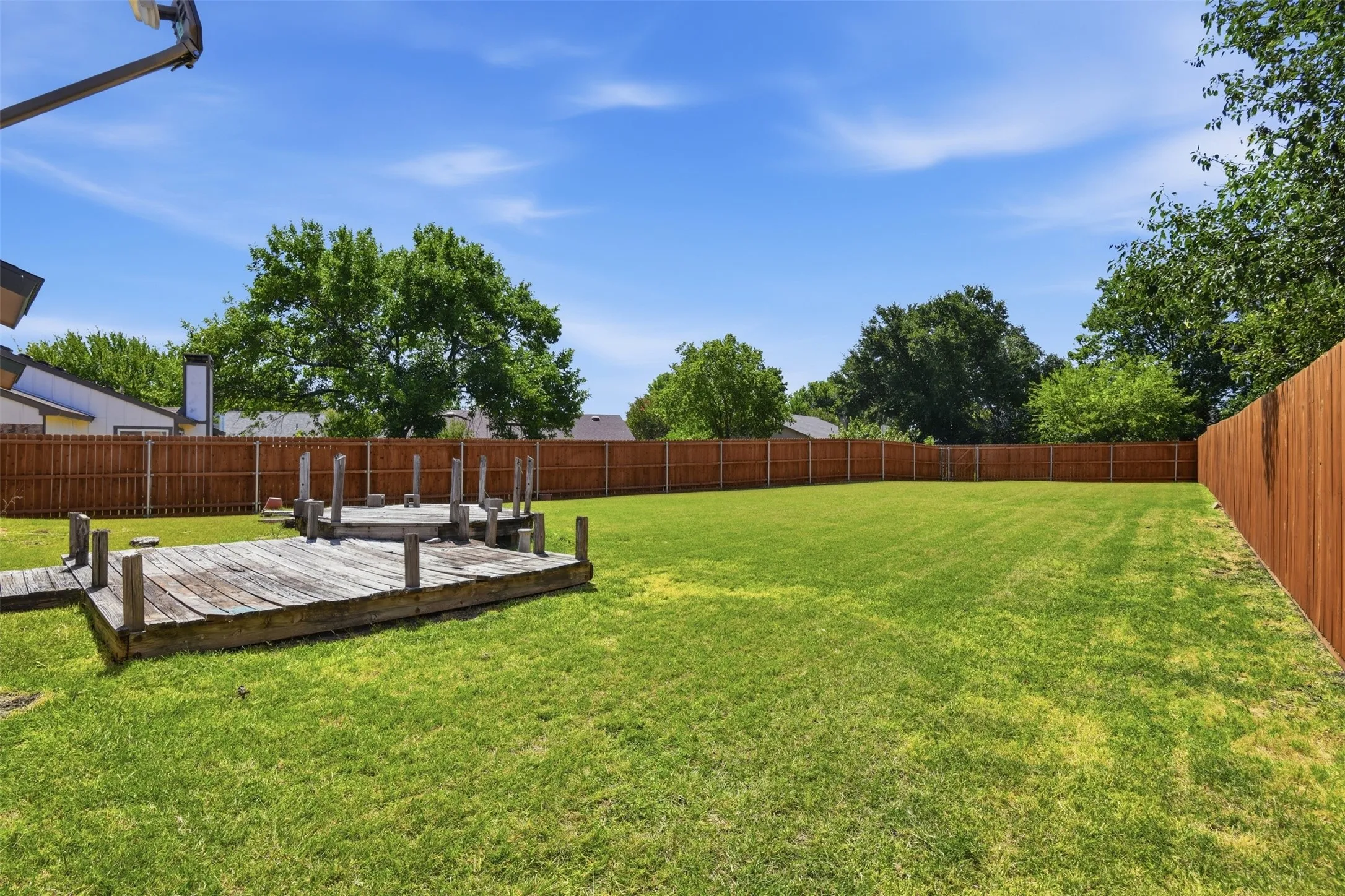 Expansive lawn area, full privacy fencing, and a built-in wood deck structure