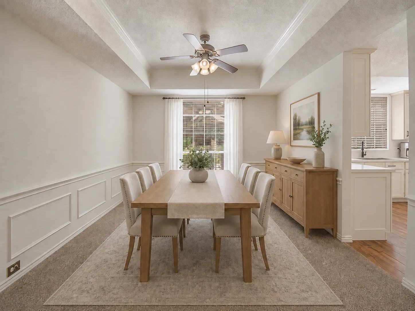 Tray ceiling with a ceiling fan, wainscoting, a large window with blinds, and carpeted flooring