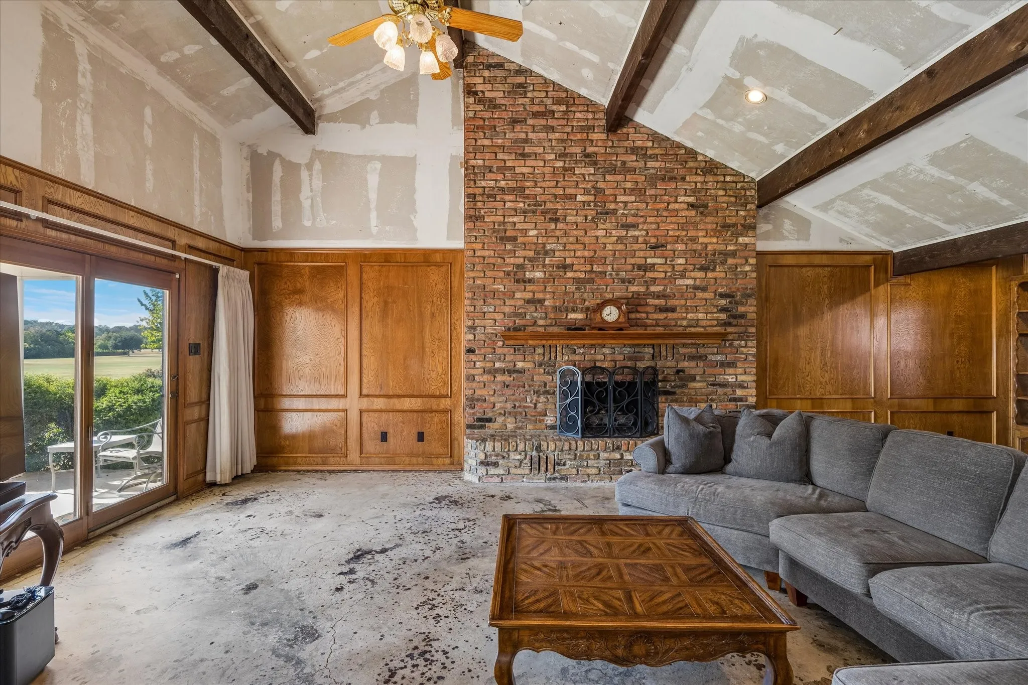 Living area overlooks the golf course, gas fireplace with logs. needs flooring and there is sheetrock behind the paneling.