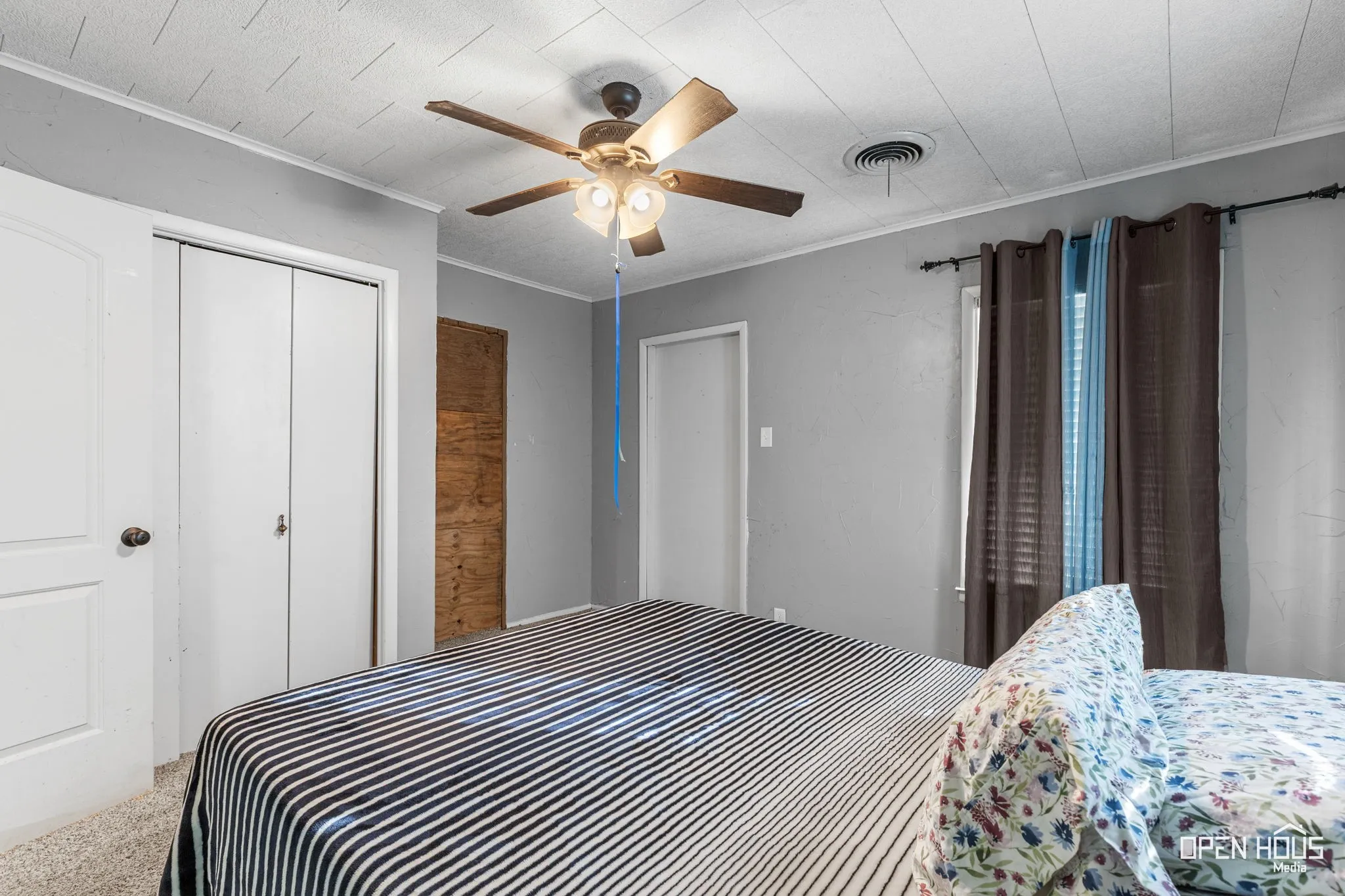 Textured ceiling with a ceiling fan, light gray wall finish, and neutral carpeting