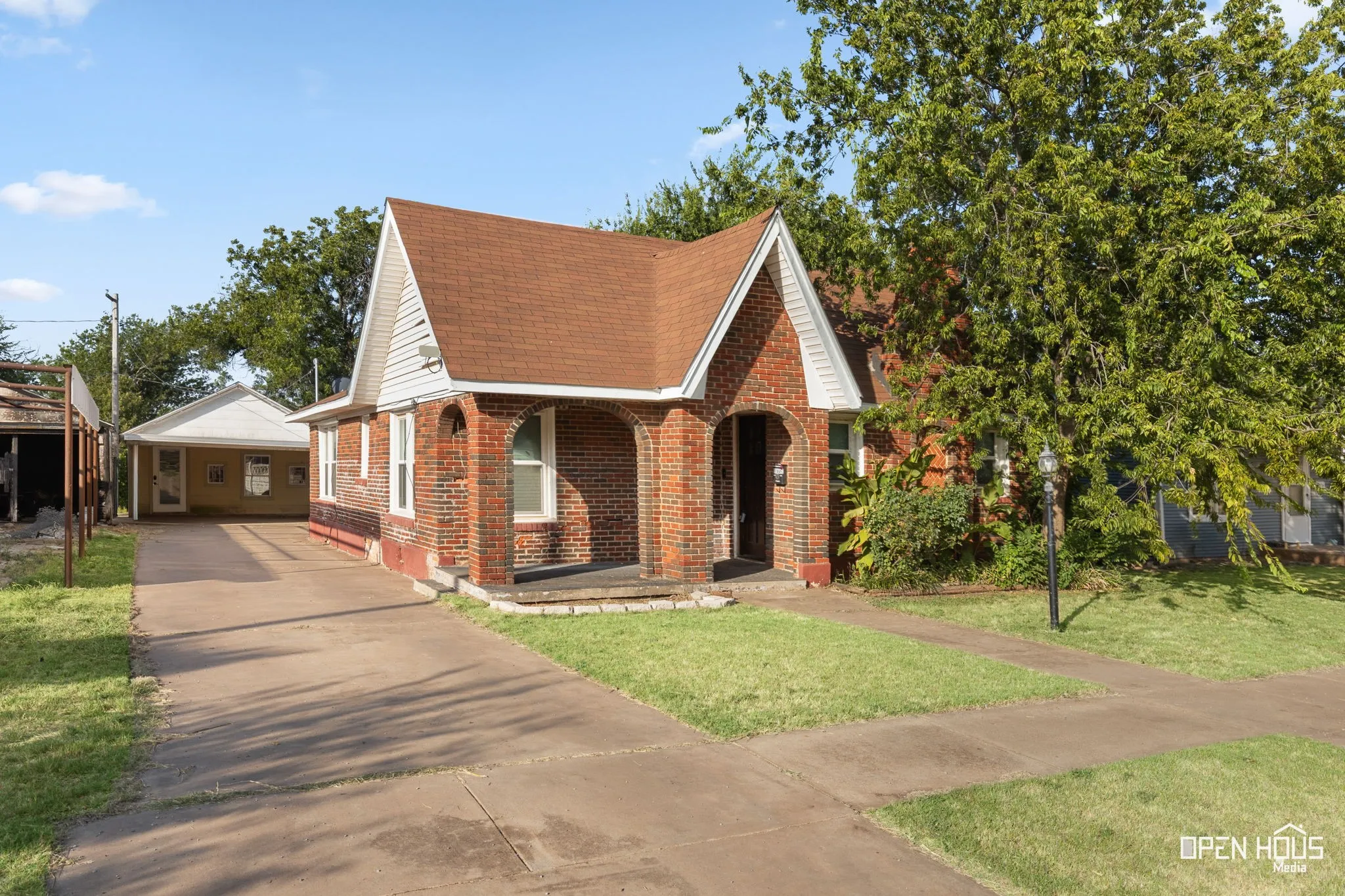 Brick exterior with arched entryway, steep gabled roofline, and front lawn