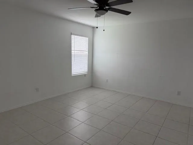 White walls, tile flooring, and a ceiling fan with integrated lighting
