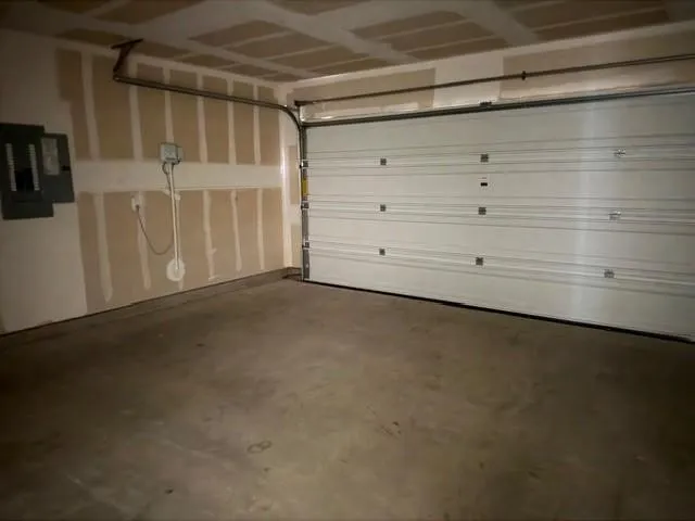Garage featuring a concrete floor, a white paneled garage door, and visible wall framing
