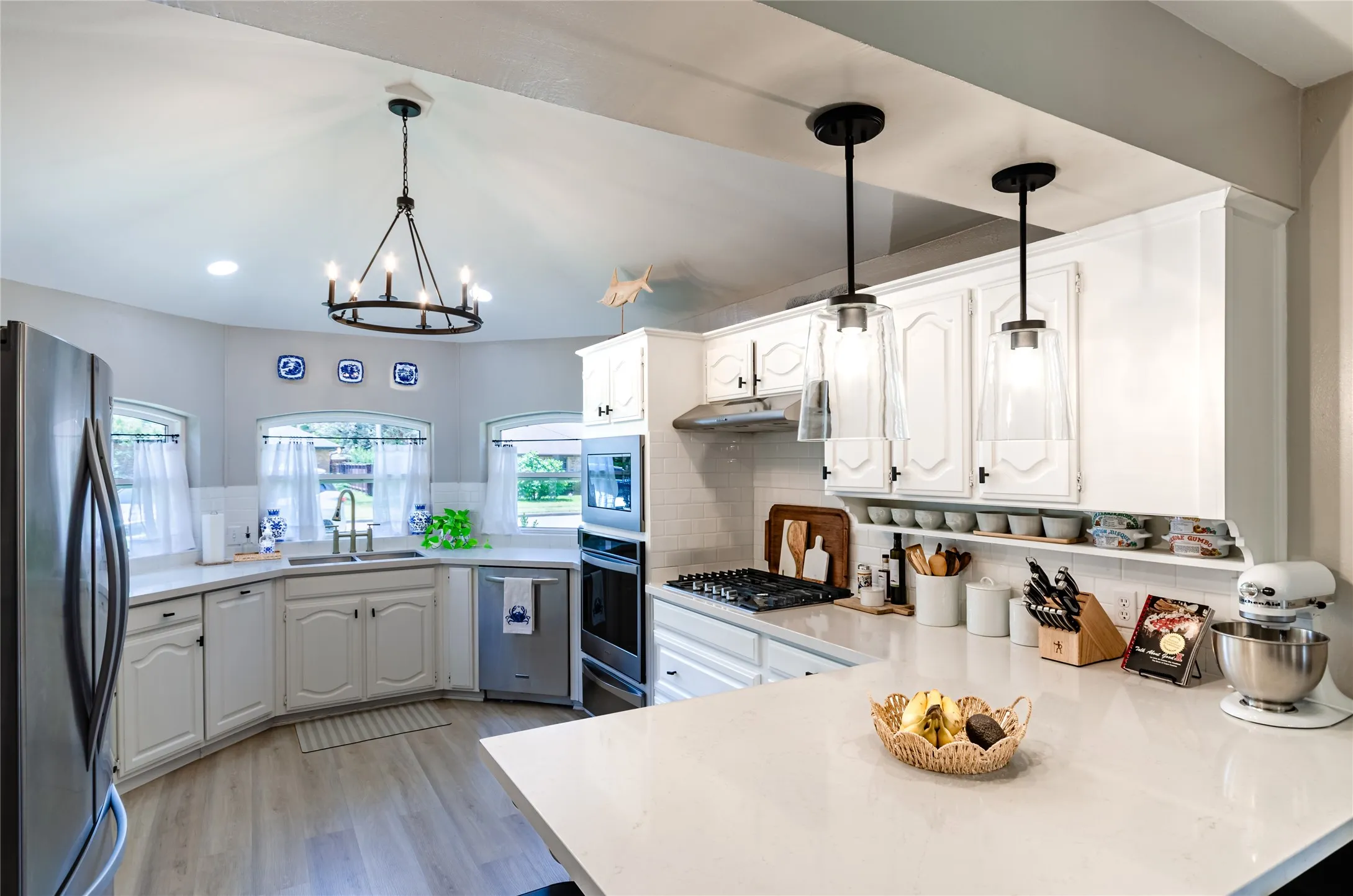White cabinetry, stainless steel appliances, built-in microwave, gas cooktop, and light-toned countertops