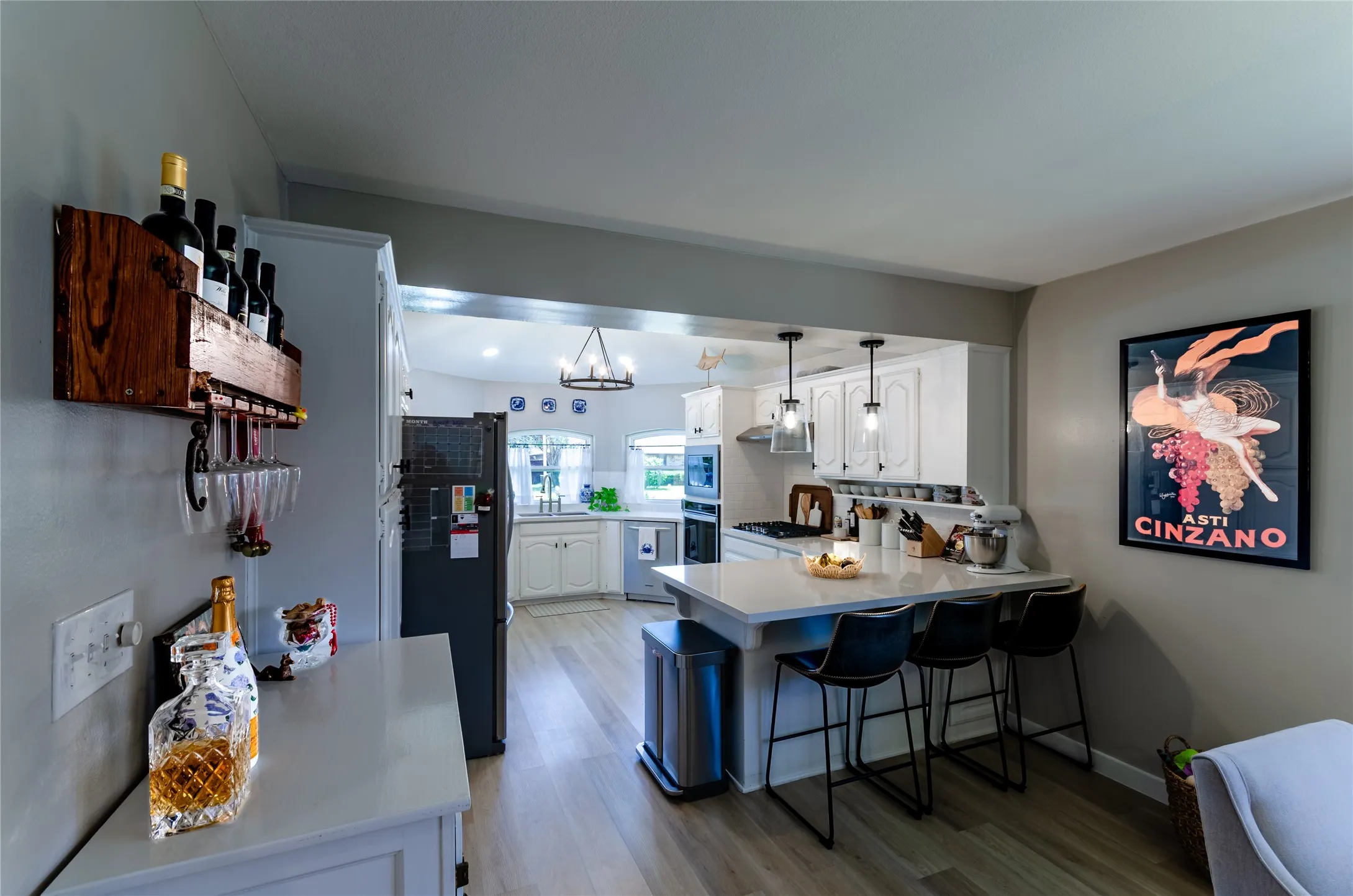 Kitchen featuring white cabinetry, a central island with countertop seating, stainless steel appliances, and pendant lighting