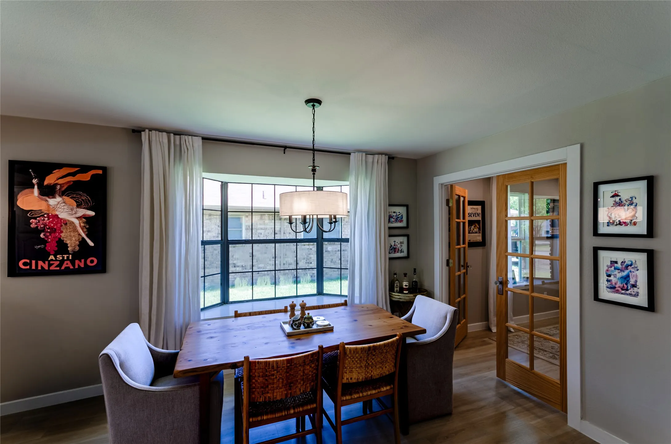 Wood-finish flooring, bay window, chandelier light fixture, French doors, and neutral wall tones