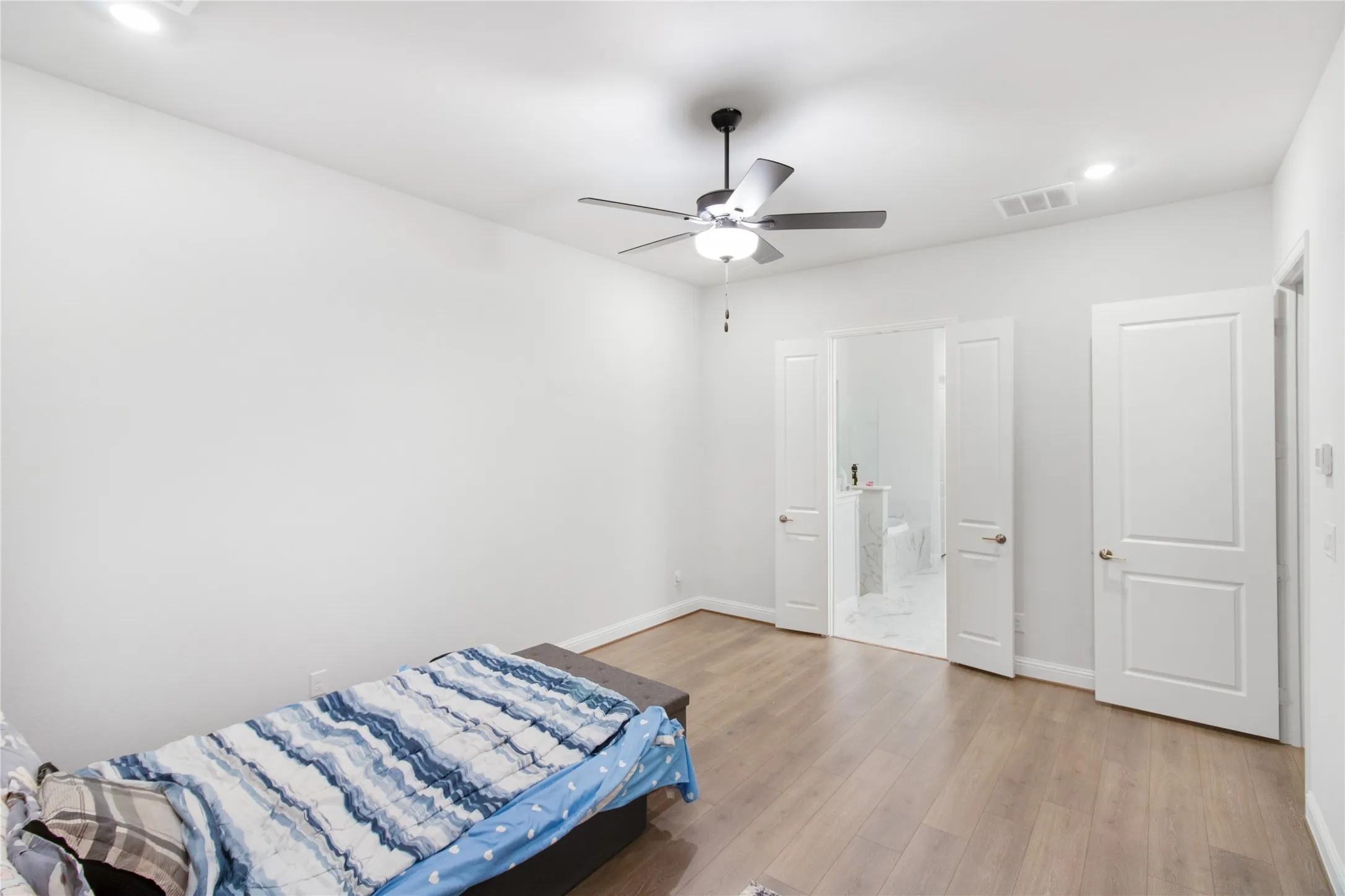 Wood-finish flooring, recessed lighting, ceiling fan with integrated light, and white paneled doors