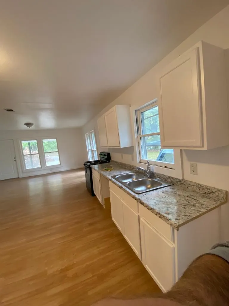 Kitchen area featuring white cabinetry, granite countertops, a dual basin stainless steel sink, and a black range