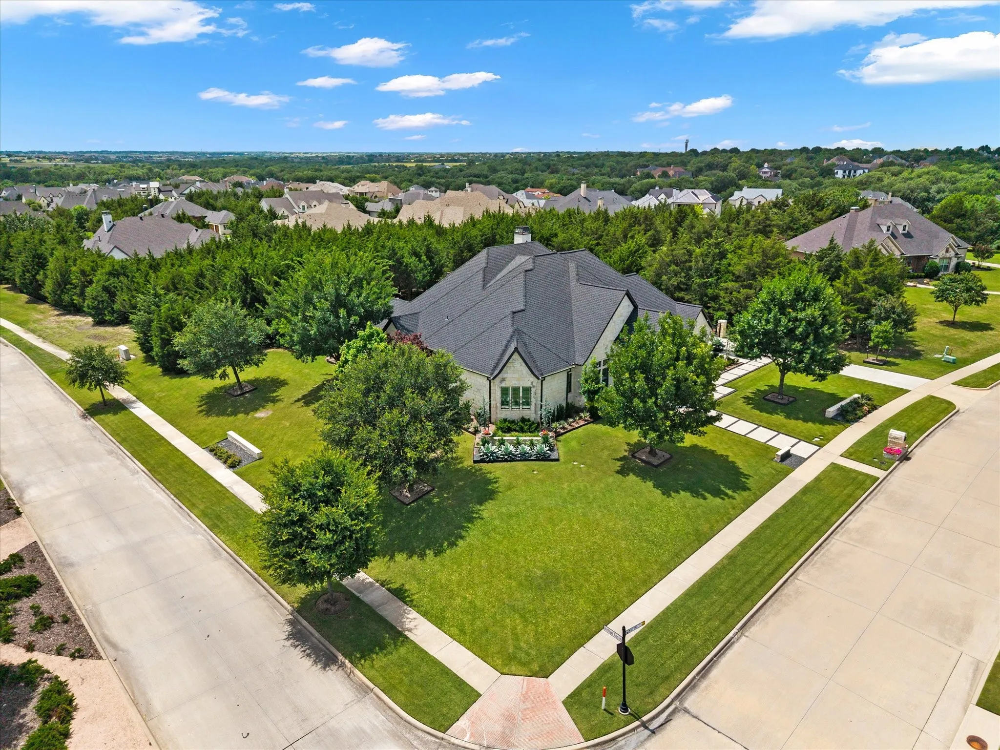 Corner lot residence with a dark shingle roof and light-colored exterior