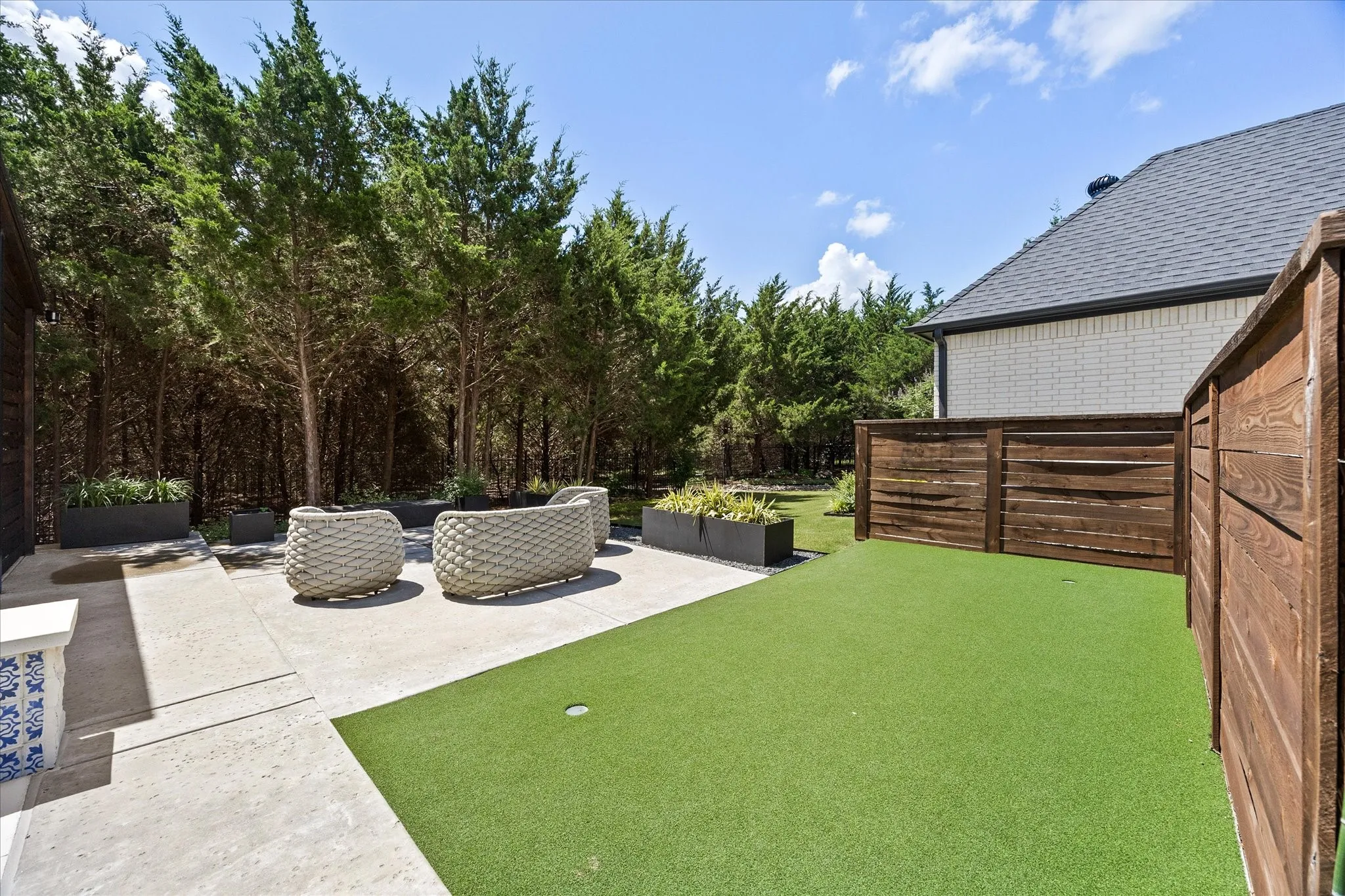 Private backyard featuring a putting green, concrete patio, and a wood privacy fence