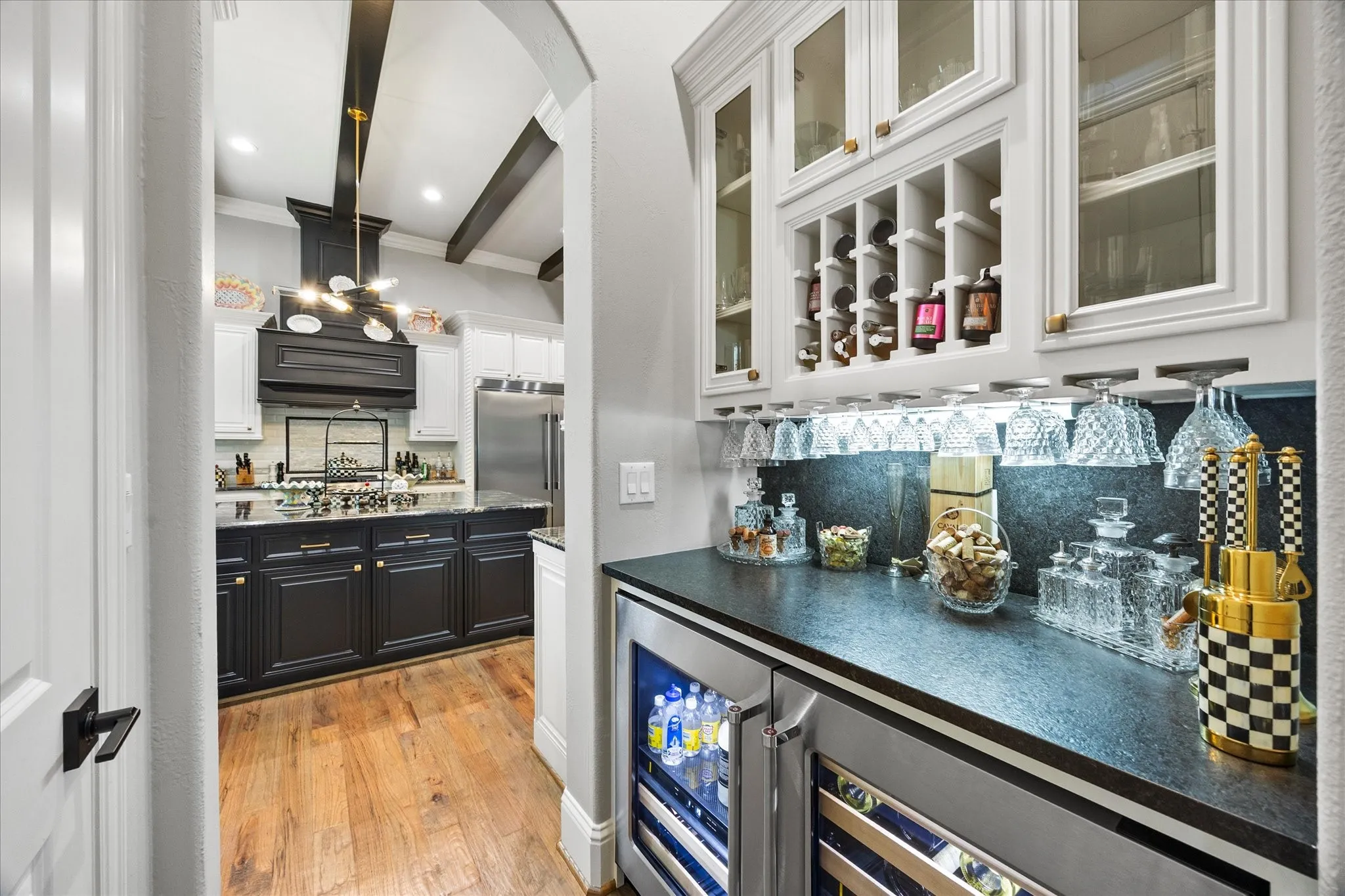 Built-in wet bar with a dark countertop and upper cabinetry featuring glass fronts and integrated wine storage