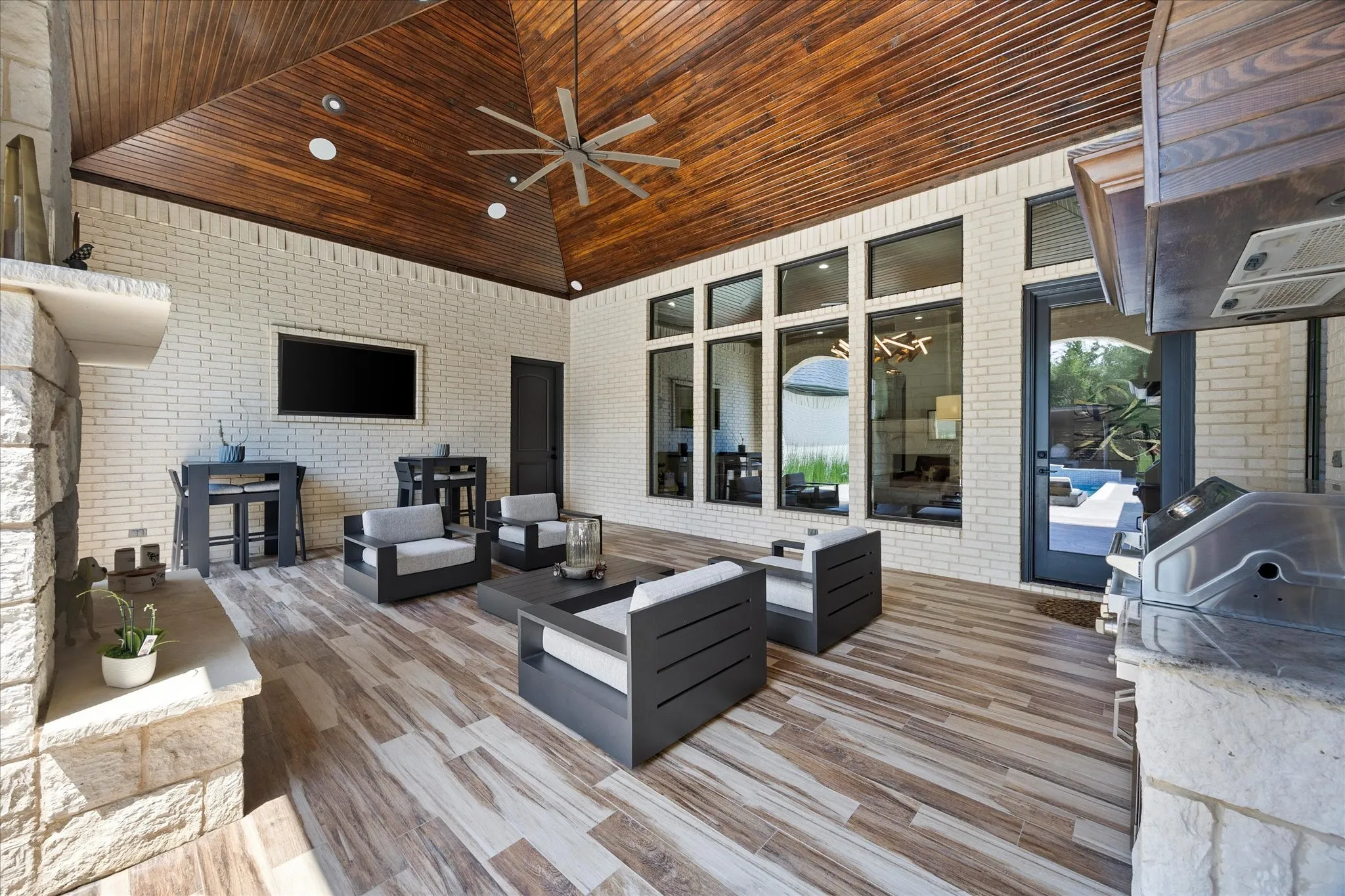 Vaulted wood-paneled ceiling with an installed ceiling fan, white brick walls, and wood-finish flooring