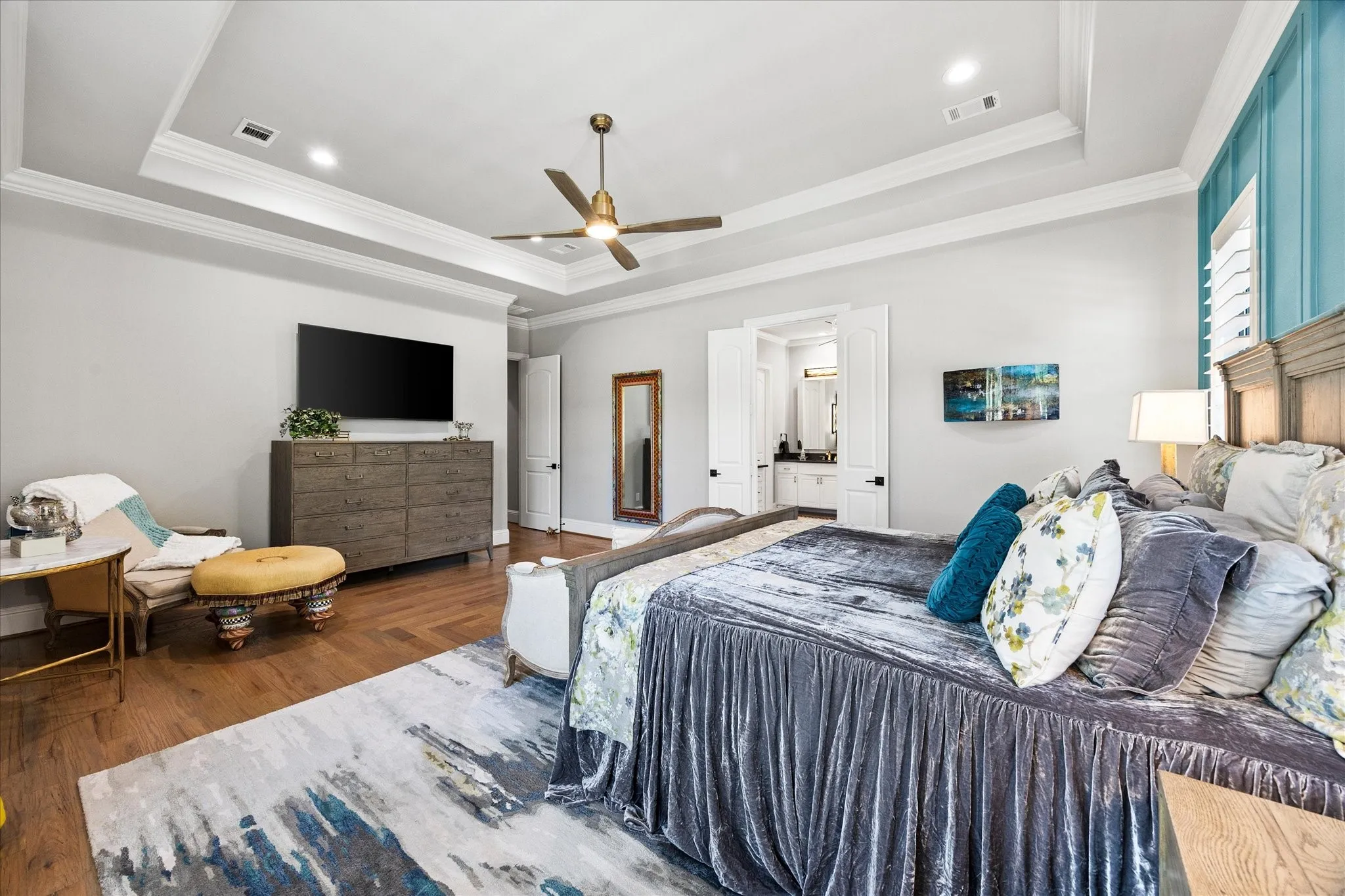 Tray ceiling with recessed lighting and a ceiling fan, wood-finish flooring, and white plantation shutters