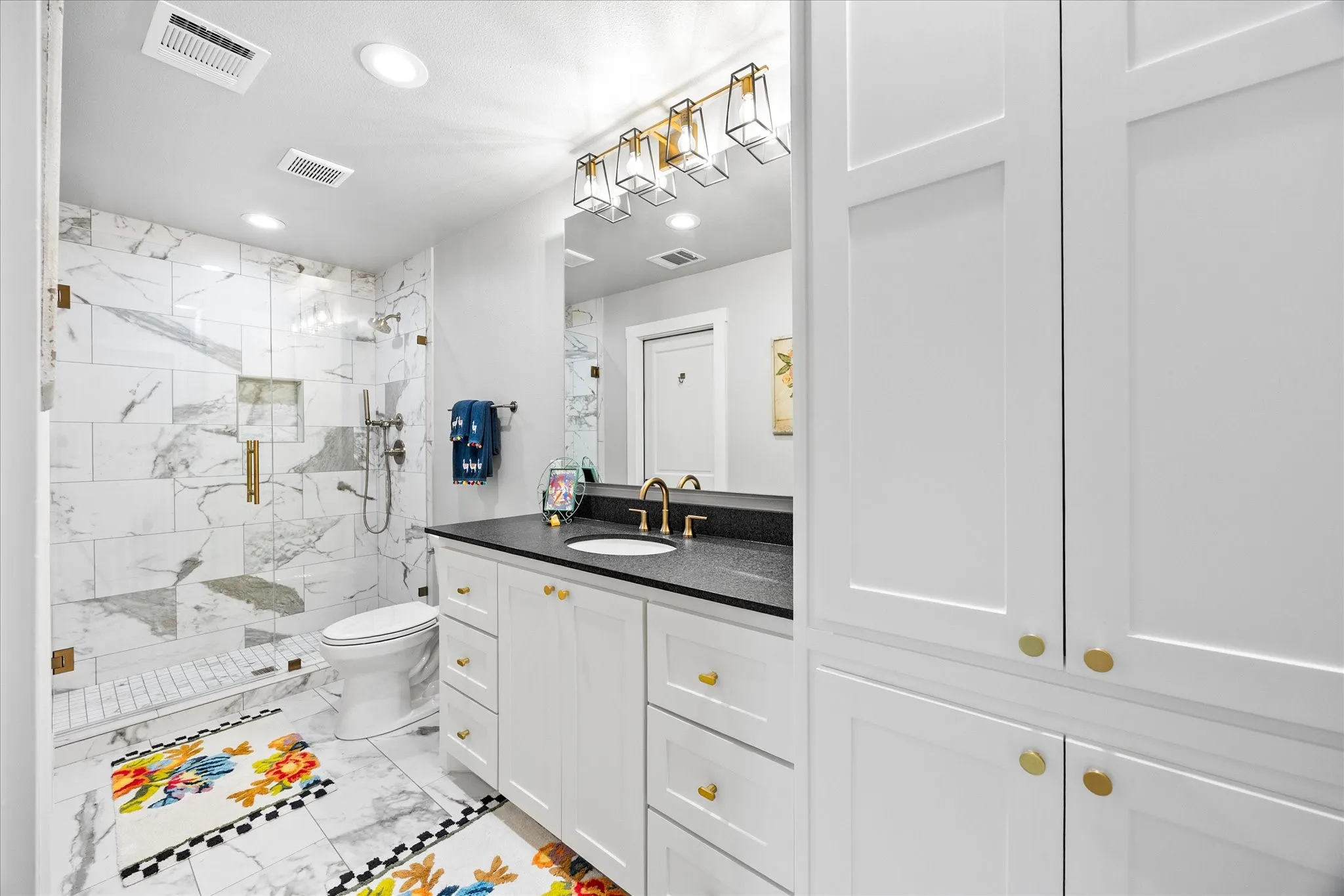 Shower with marble-patterned tile, glass enclosure, and gold-finish fixtures