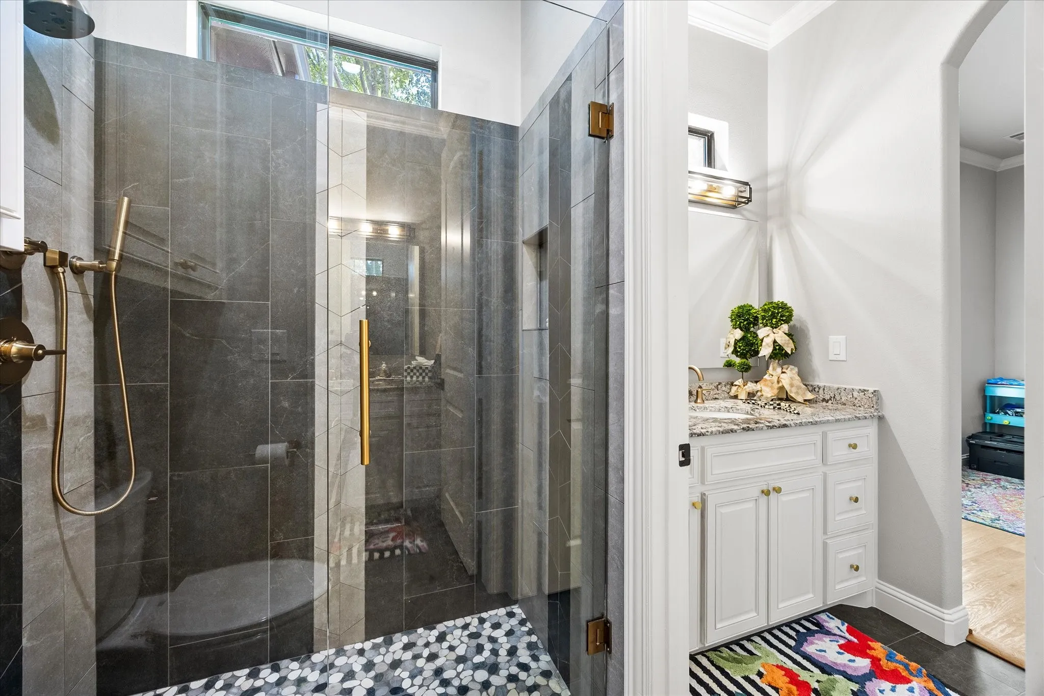 Glass-enclosed shower with dark tile surround, a built-in niche, and a contrasting mosaic tile floor