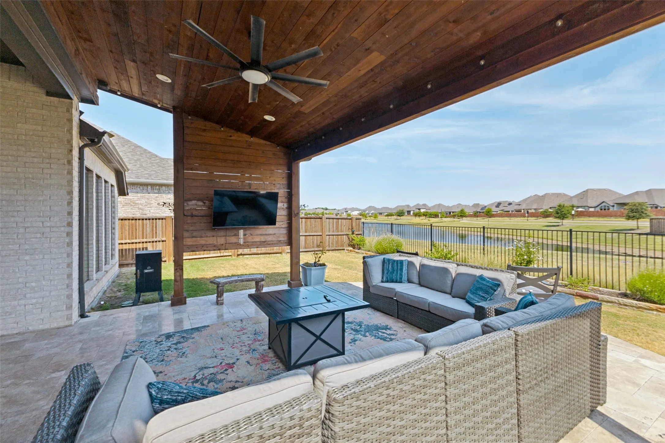 Covered outdoor patio featuring a wood-plank ceiling, ceiling fan, recessed lighting, and a mounted flat-screen