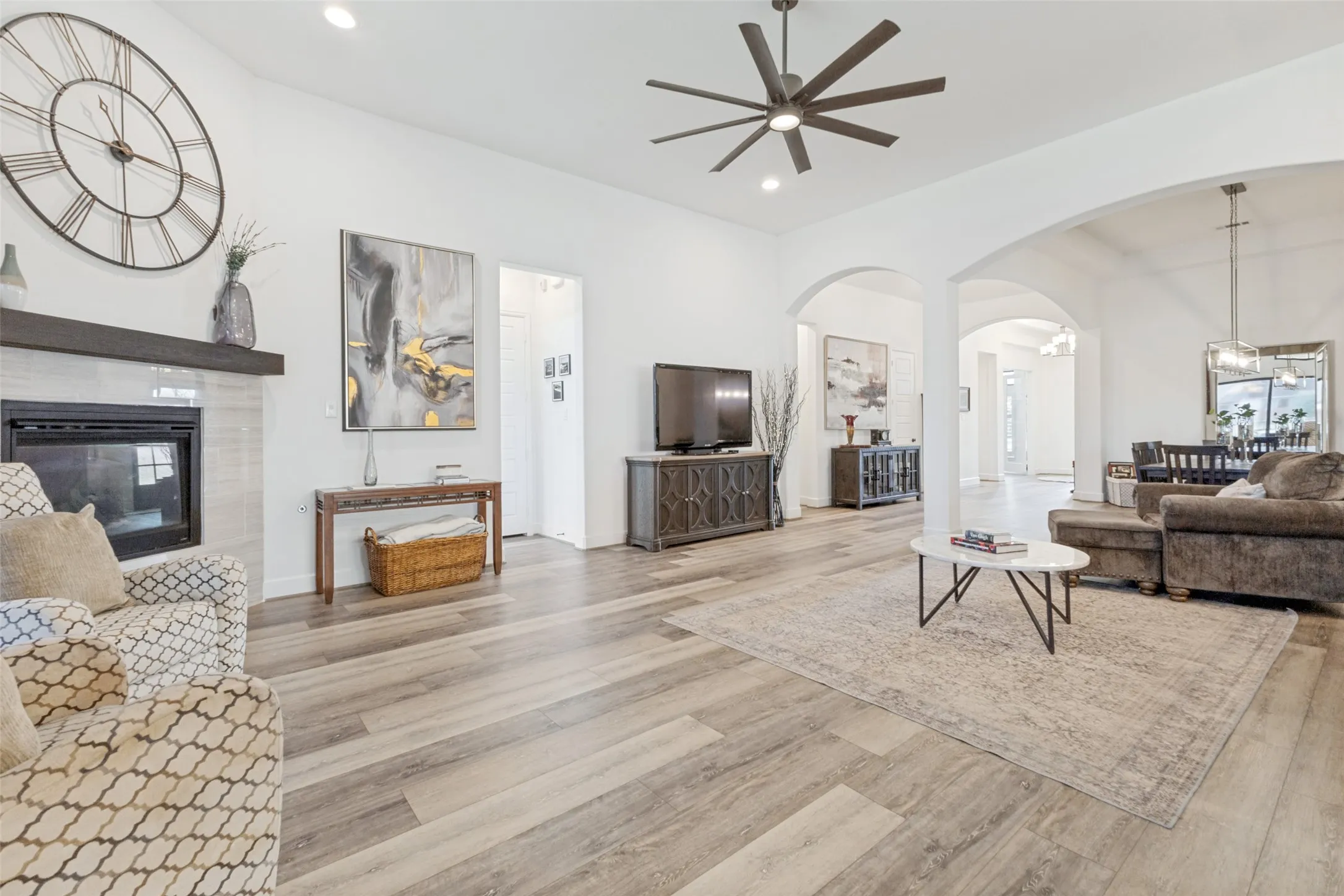 Spacious interior featuring wood-finish flooring, a tile-surround fireplace with a dark wood mantel, and arched doorways