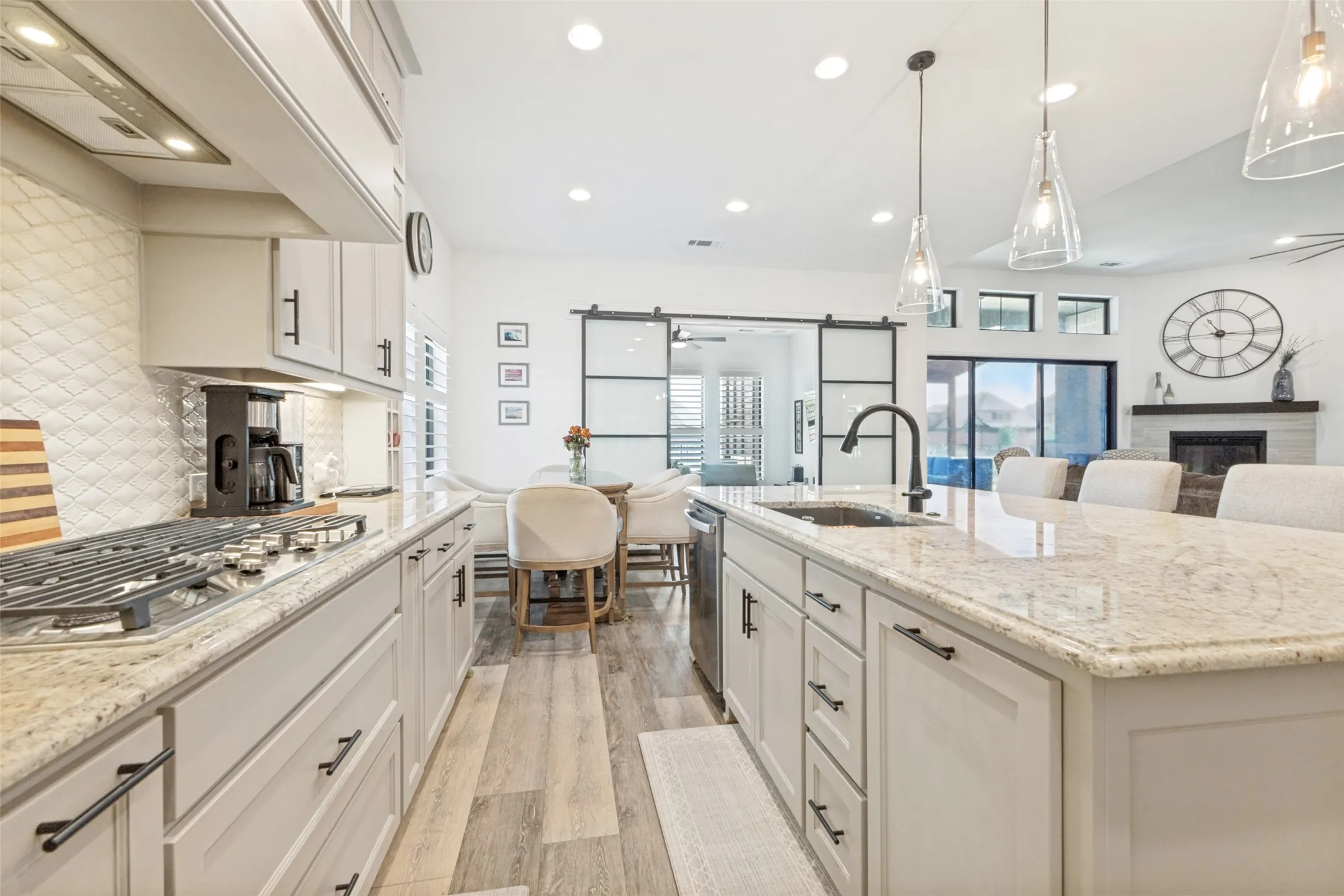 Kitchen featuring light cabinetry with dark hardware, stone countertops, a gas range, and wood-finish flooring