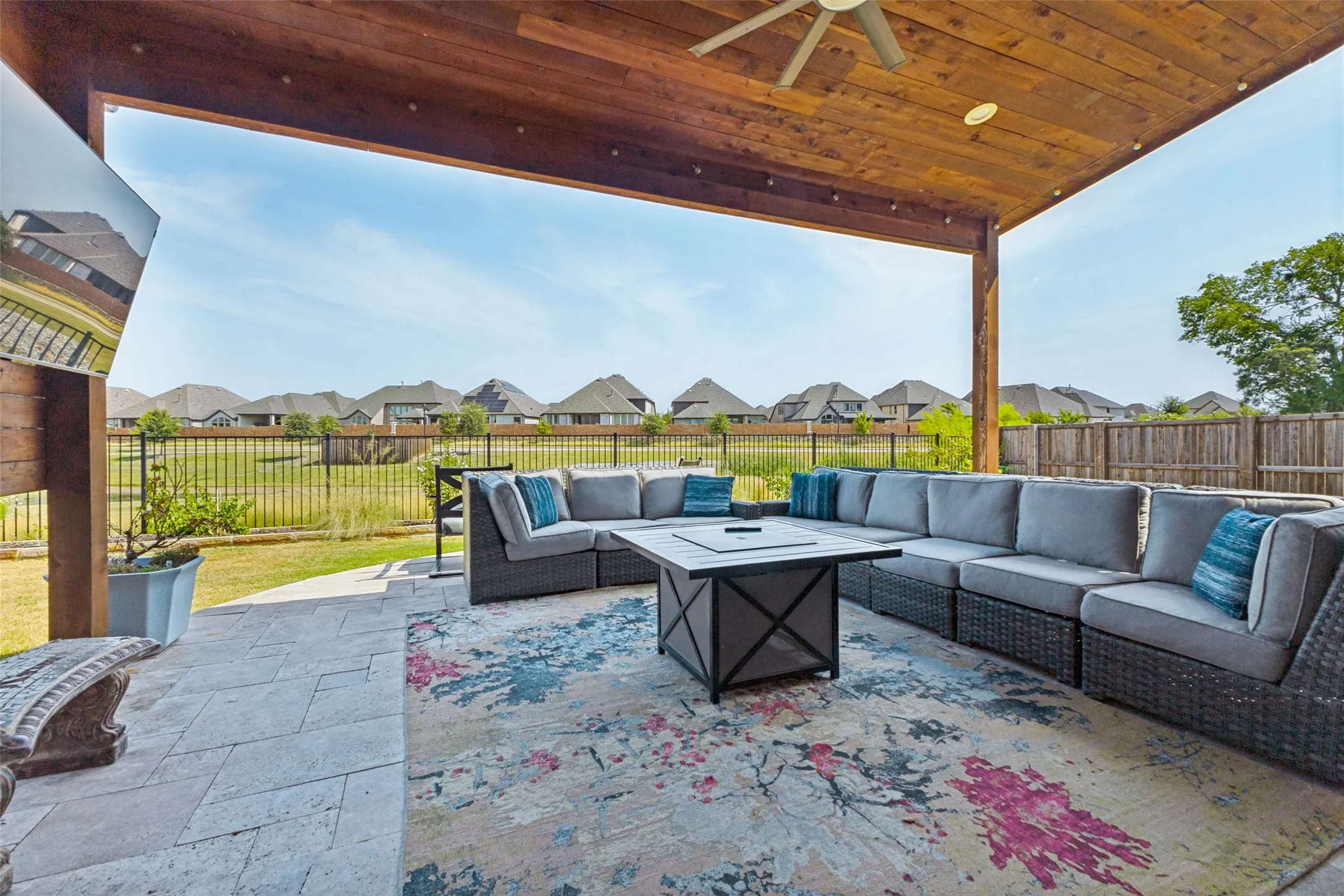 Expansive covered patio featuring a wood-plank ceiling, ceiling fan, recessed lighting, and a paved stone surface