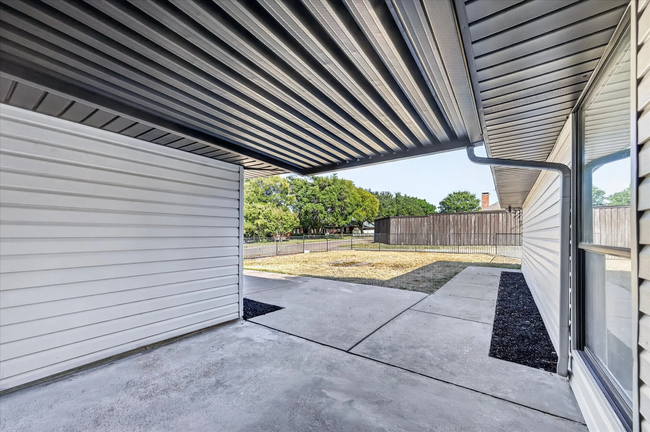 Covered patio featuring a corrugated metal roof, concrete slab, and wood-finish siding