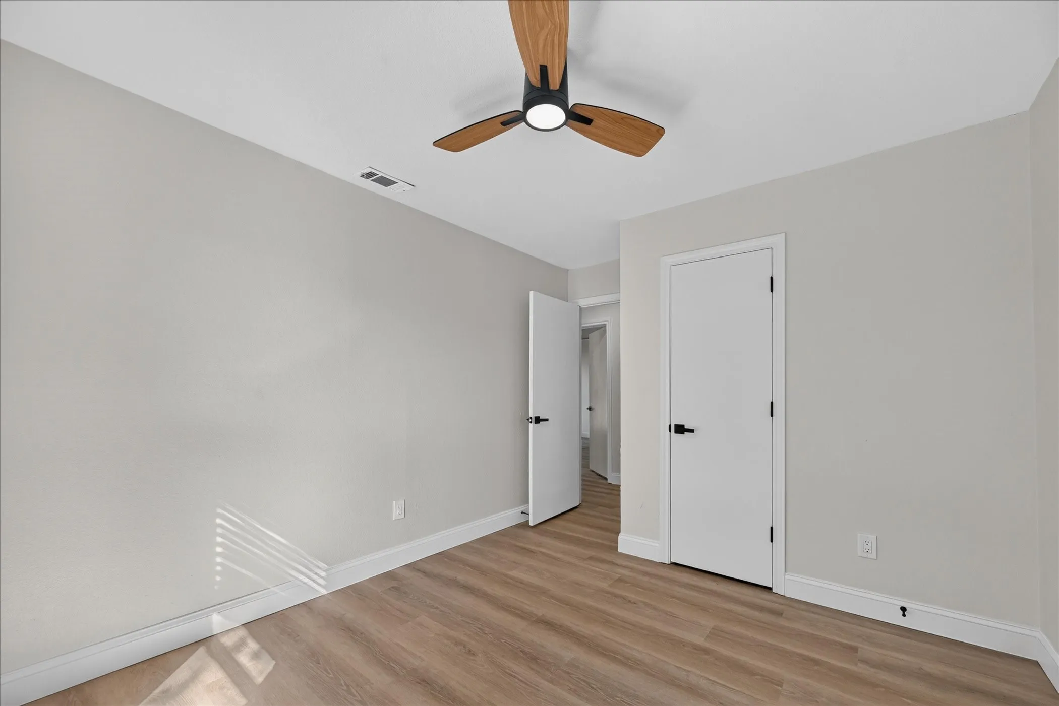 Wood-finish flooring, white trim, off-white walls, window with blinds, and a ceiling fan with light