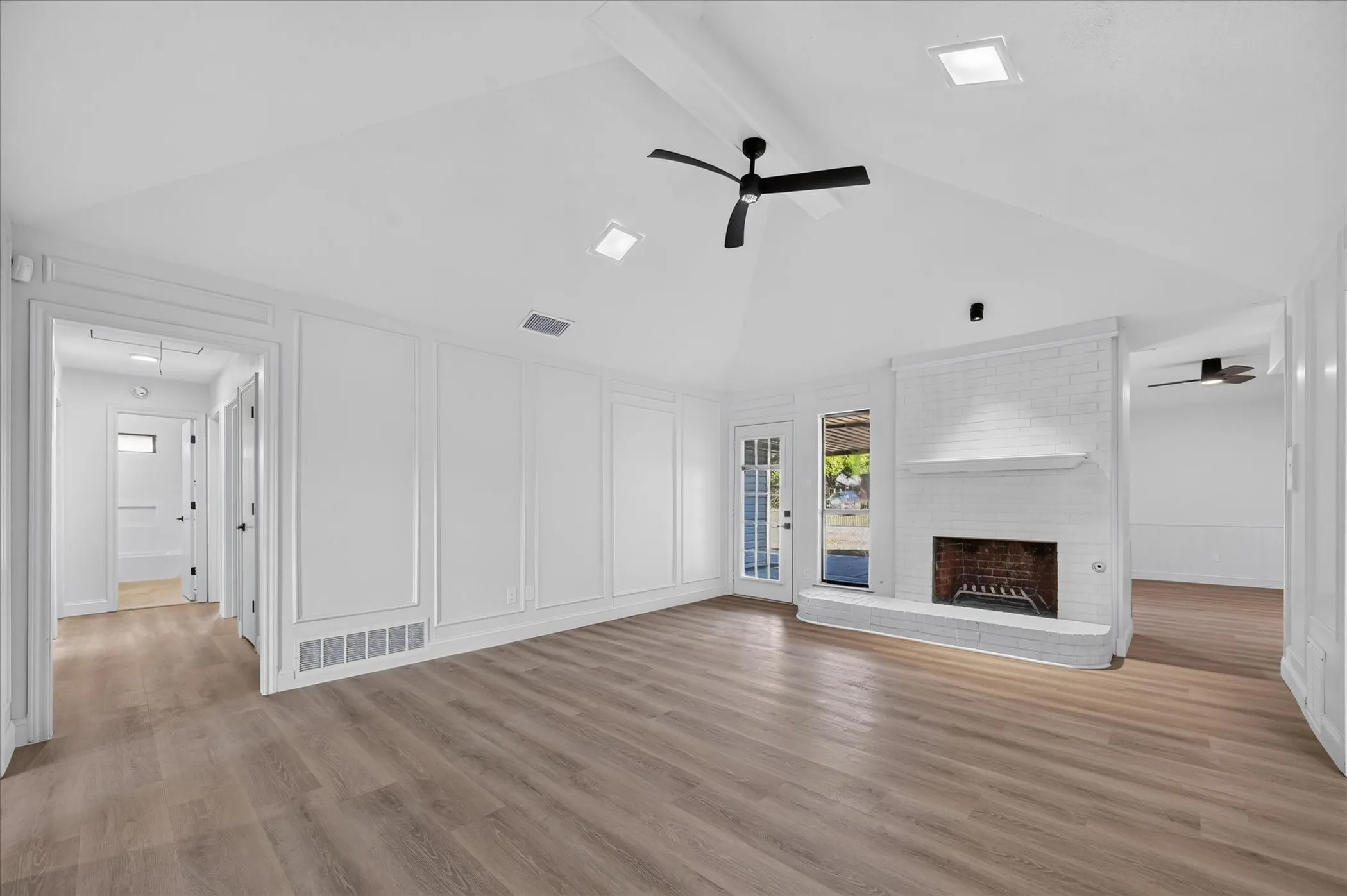 Vaulted ceilings, wood-finish flooring, white brick fireplace, panel molding details, and recessed lighting