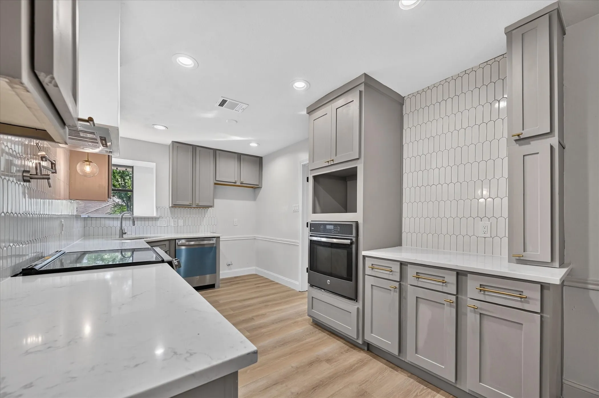 Modern Kitchen featuring taupe cabinetry, white countertops, wood-finish flooring, a stainless steel range, and a white picket tile backsplash