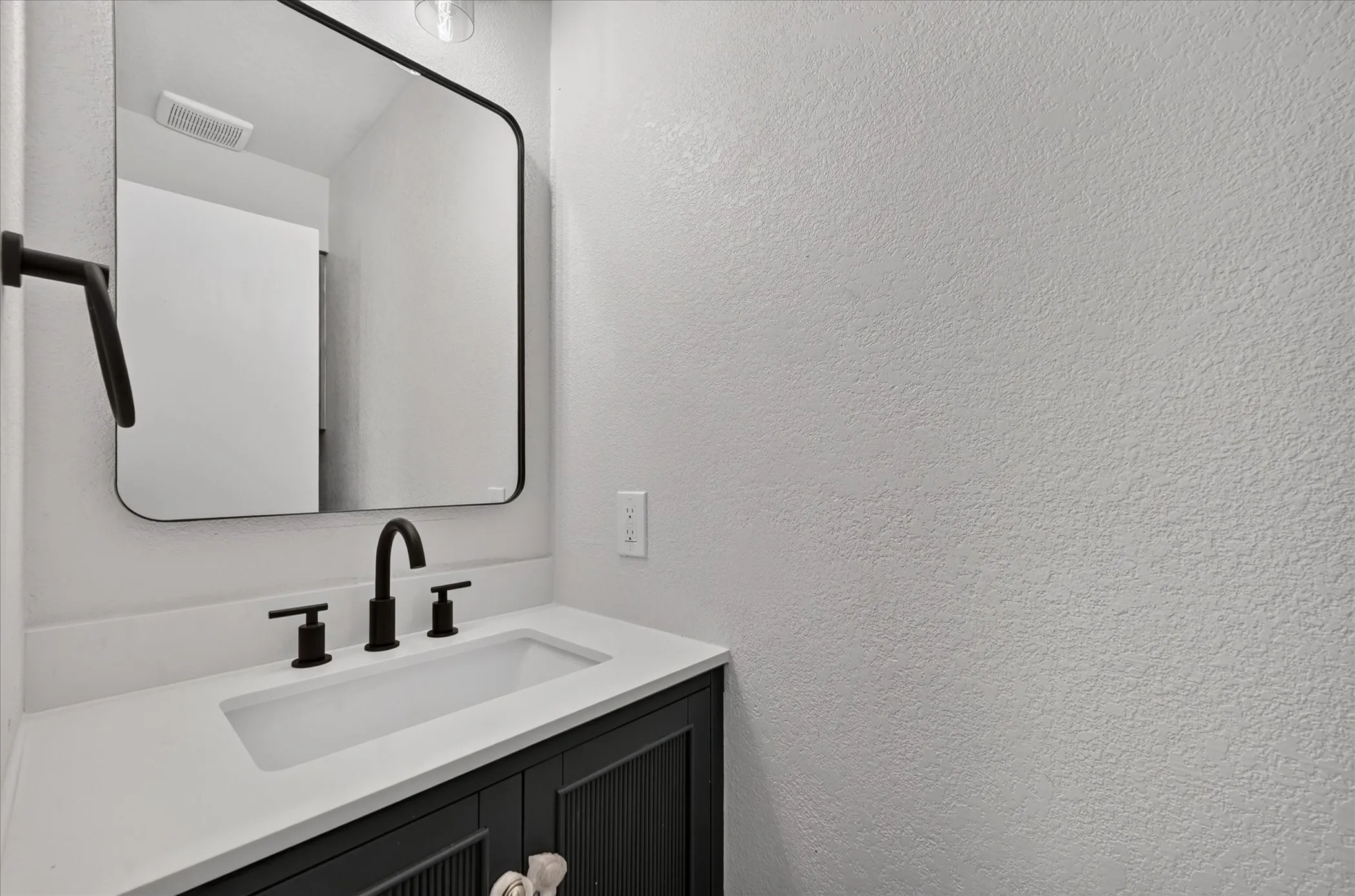 Powder Room / Half Bath. Vanity with white countertop, integrated rectangular sink, and matte black fixtures