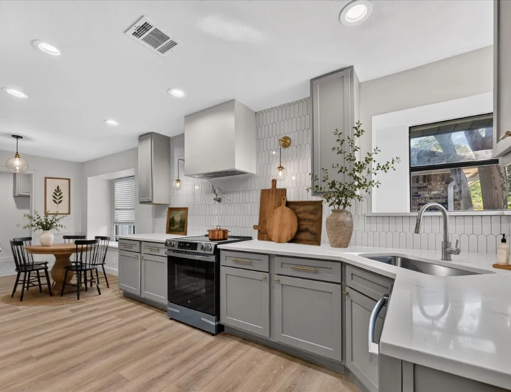 Kitchen featuring taupe cabinetry, white countertops, wood-finish flooring, a stainless steel range, and a white picket tile backsplash