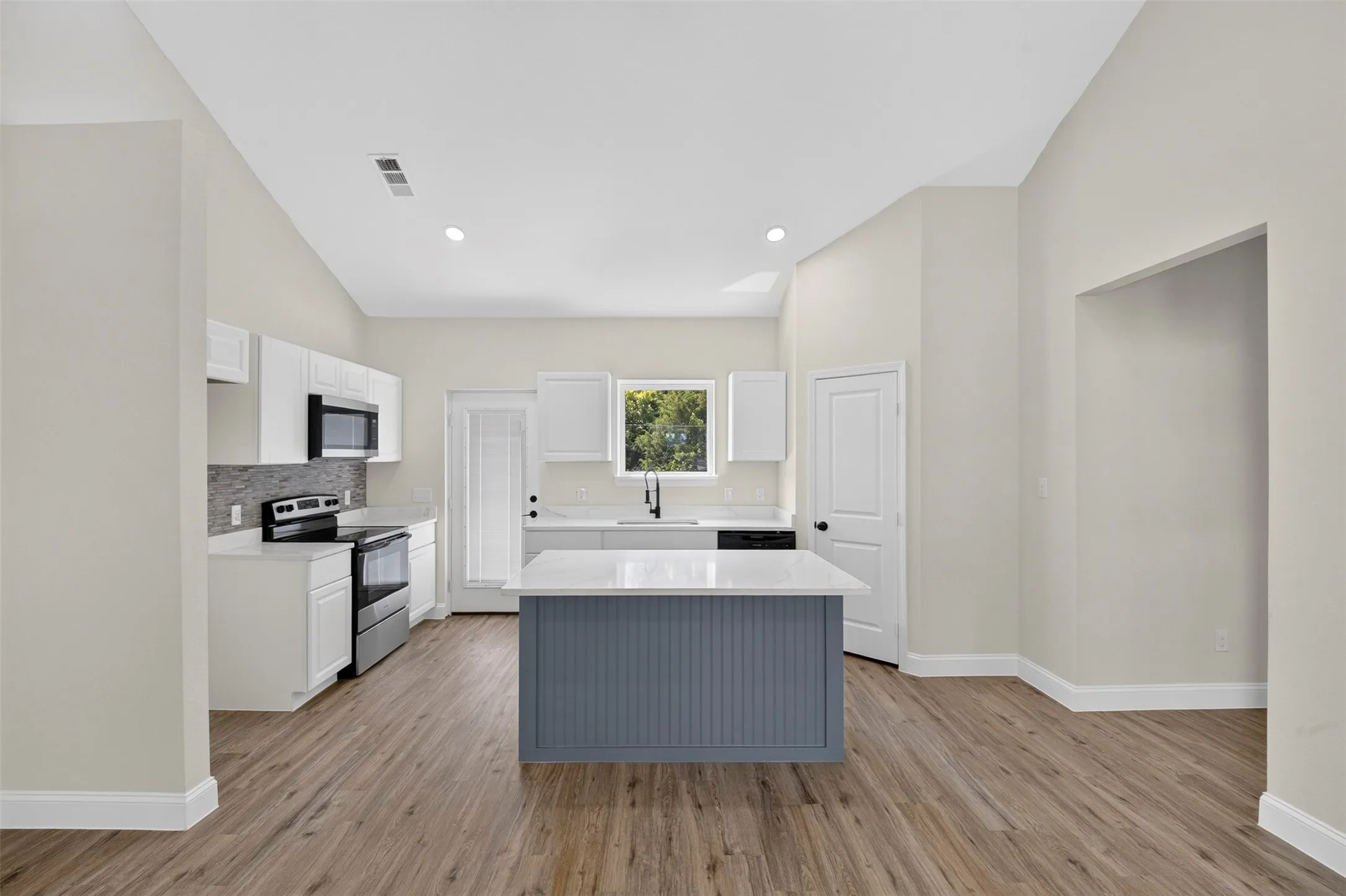 Kitchen featuring a center island with a stone countertop, wood-finish flooring, recessed lighting, and white cabinetry