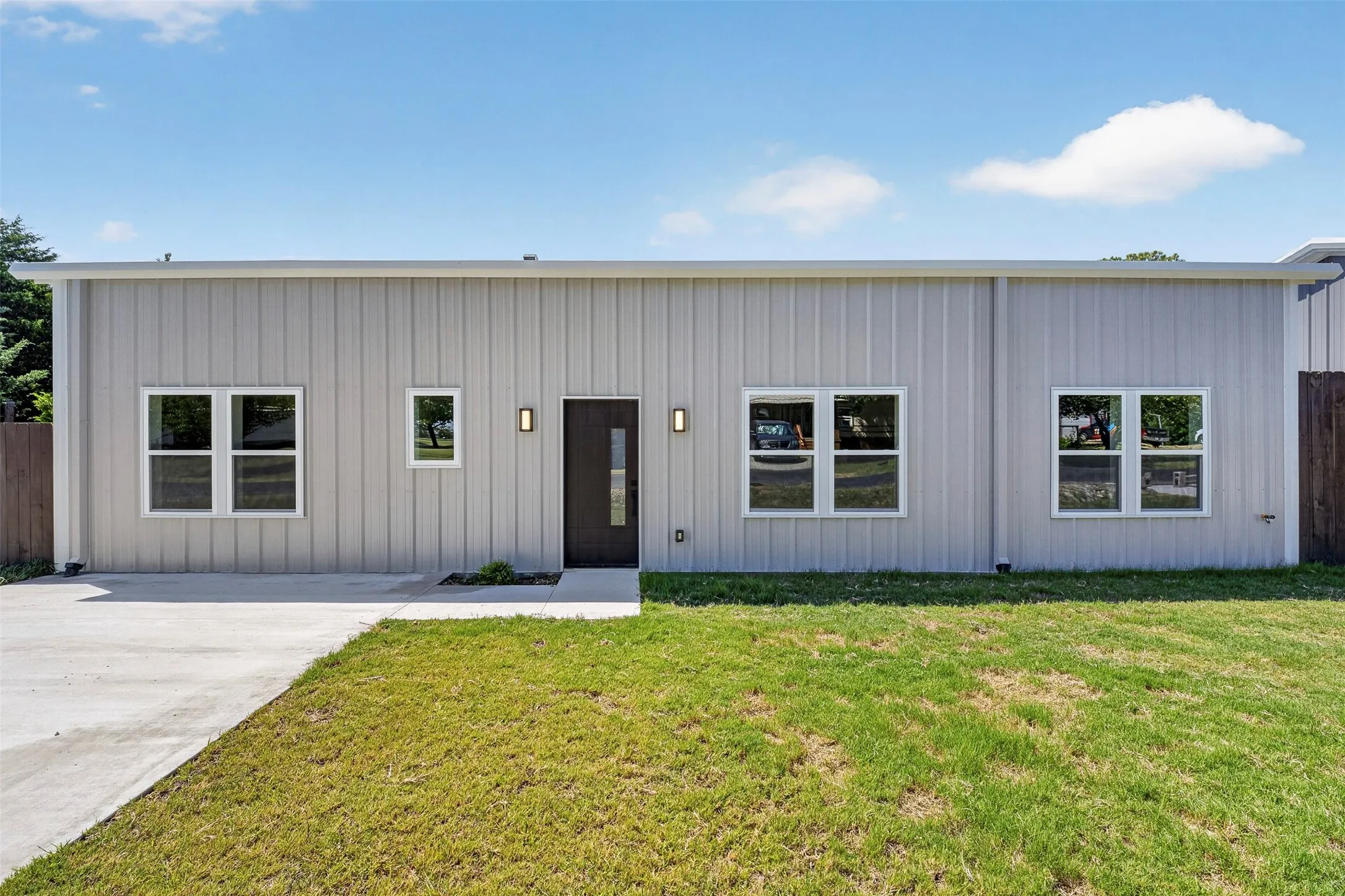 Modern exterior with vertical panel siding, dark entry door with frosted glass, and multiple windows