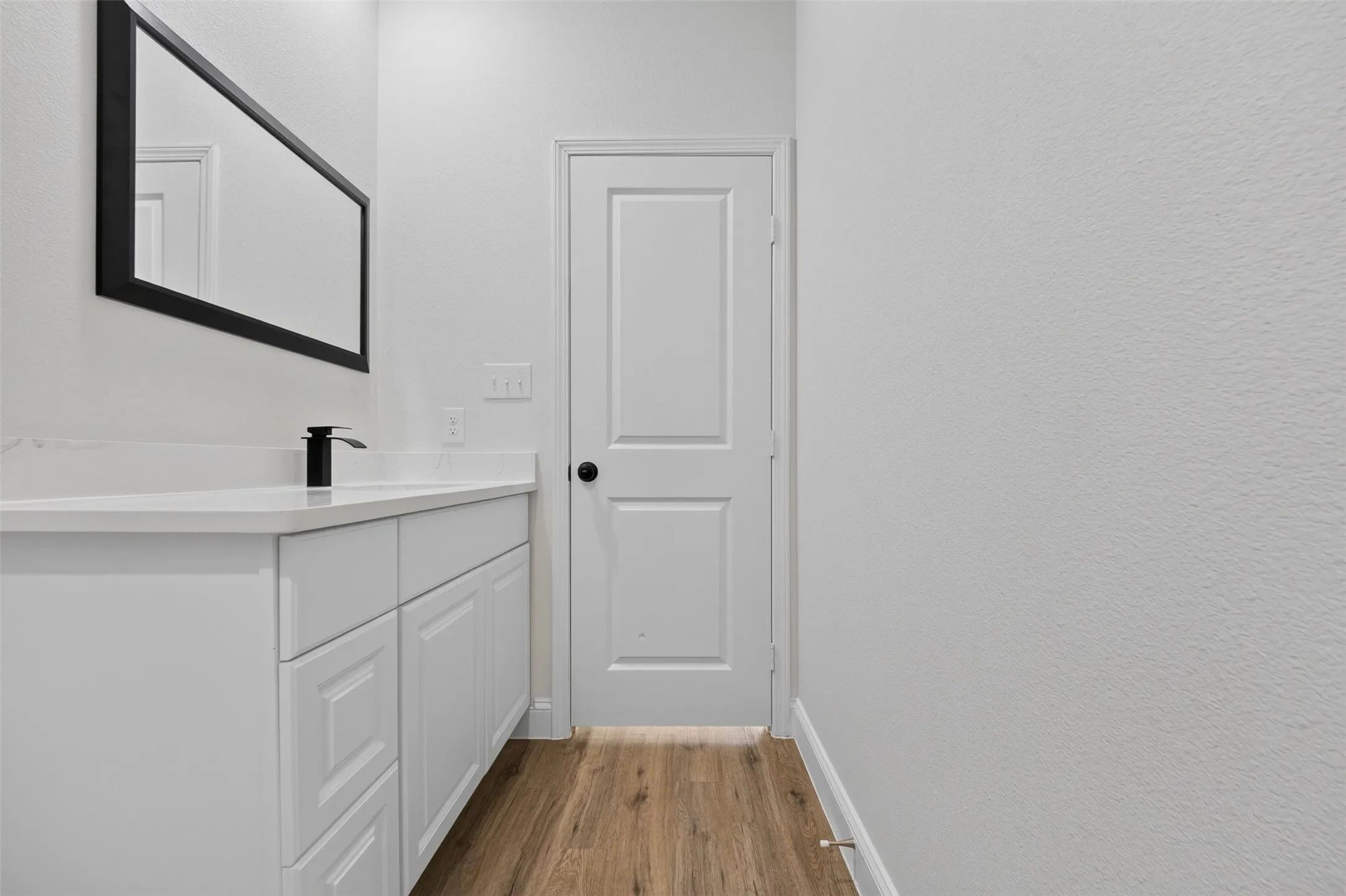 White shaker-style cabinetry with a white countertop and a matte black faucet