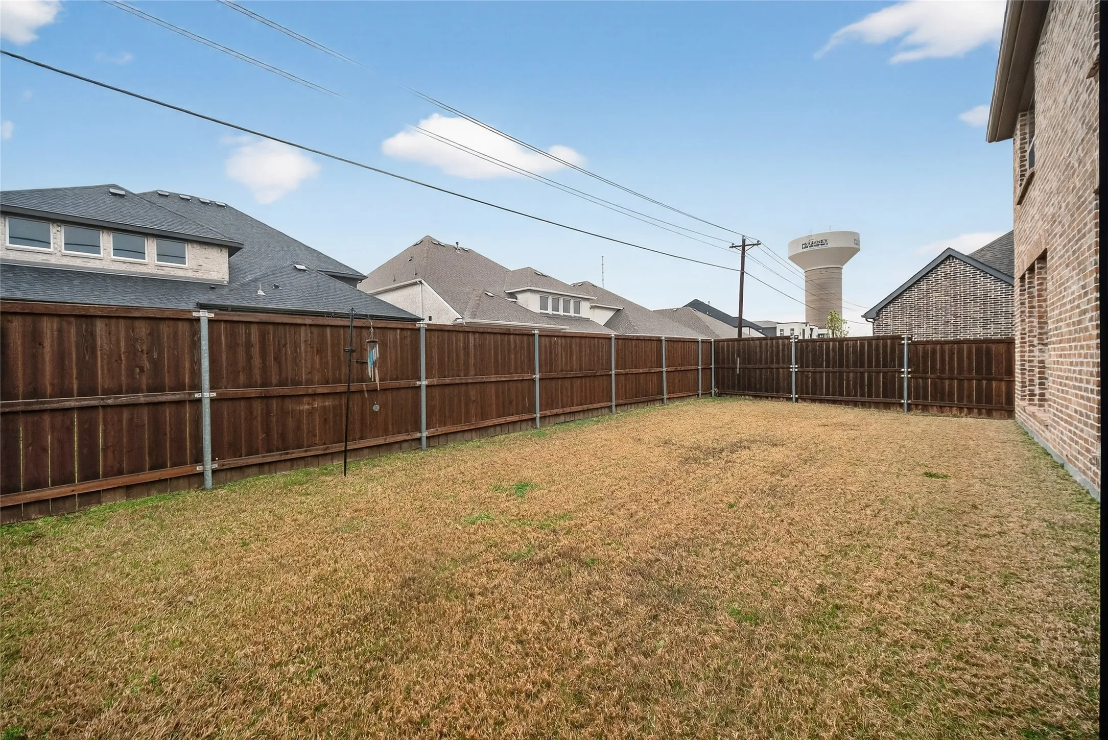 Expansive backyard featuring a wood privacy fence and a brick exterior wall