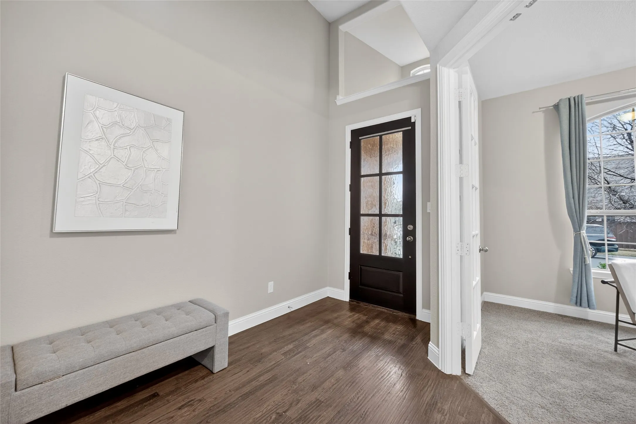 Entryway featuring a dark wood-finish door with frosted glass panels, wood-finish flooring, and white trim