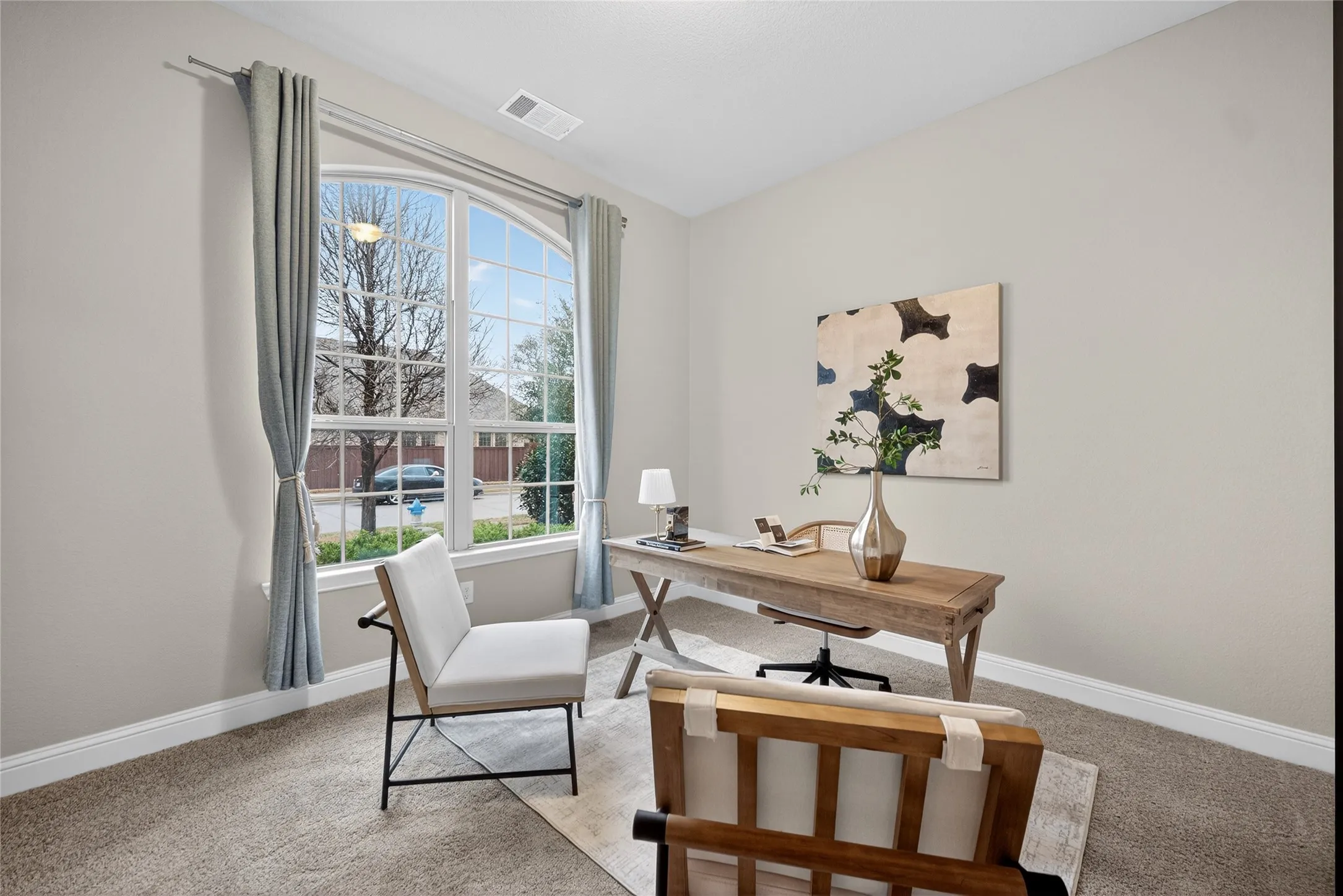 Arched window with gridded panes, light-toned walls, and carpet flooring