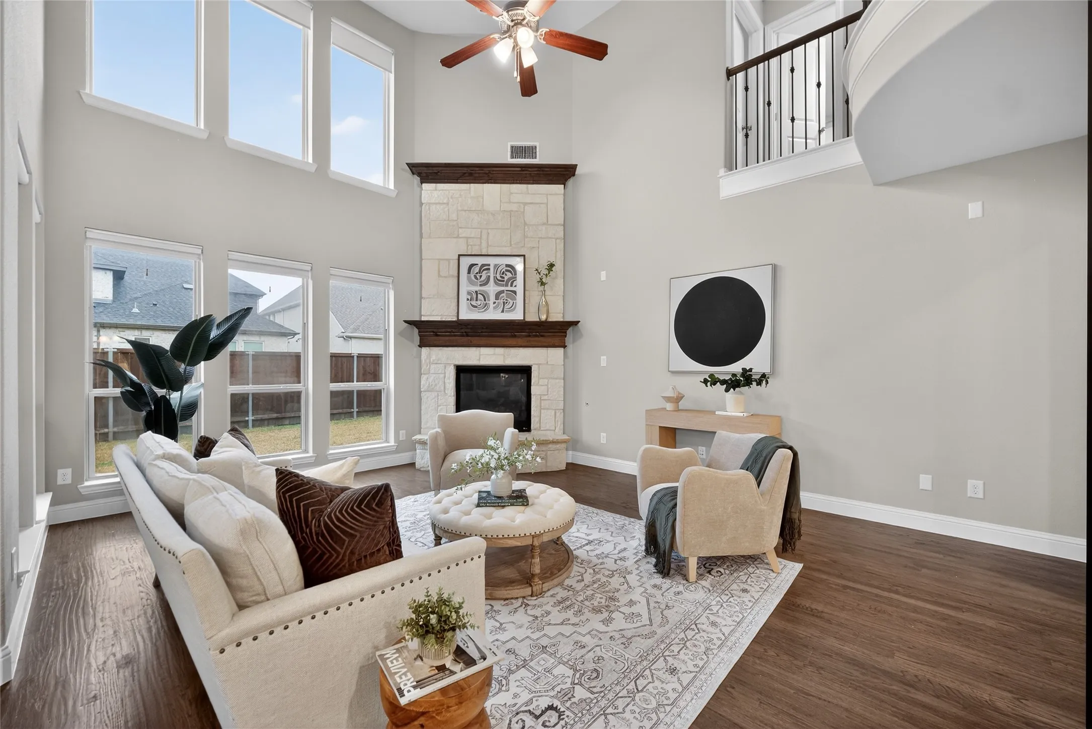 Soaring two-story living room with vaulted ceilings, ceiling fan, and abundant natural light from multi-pane windows