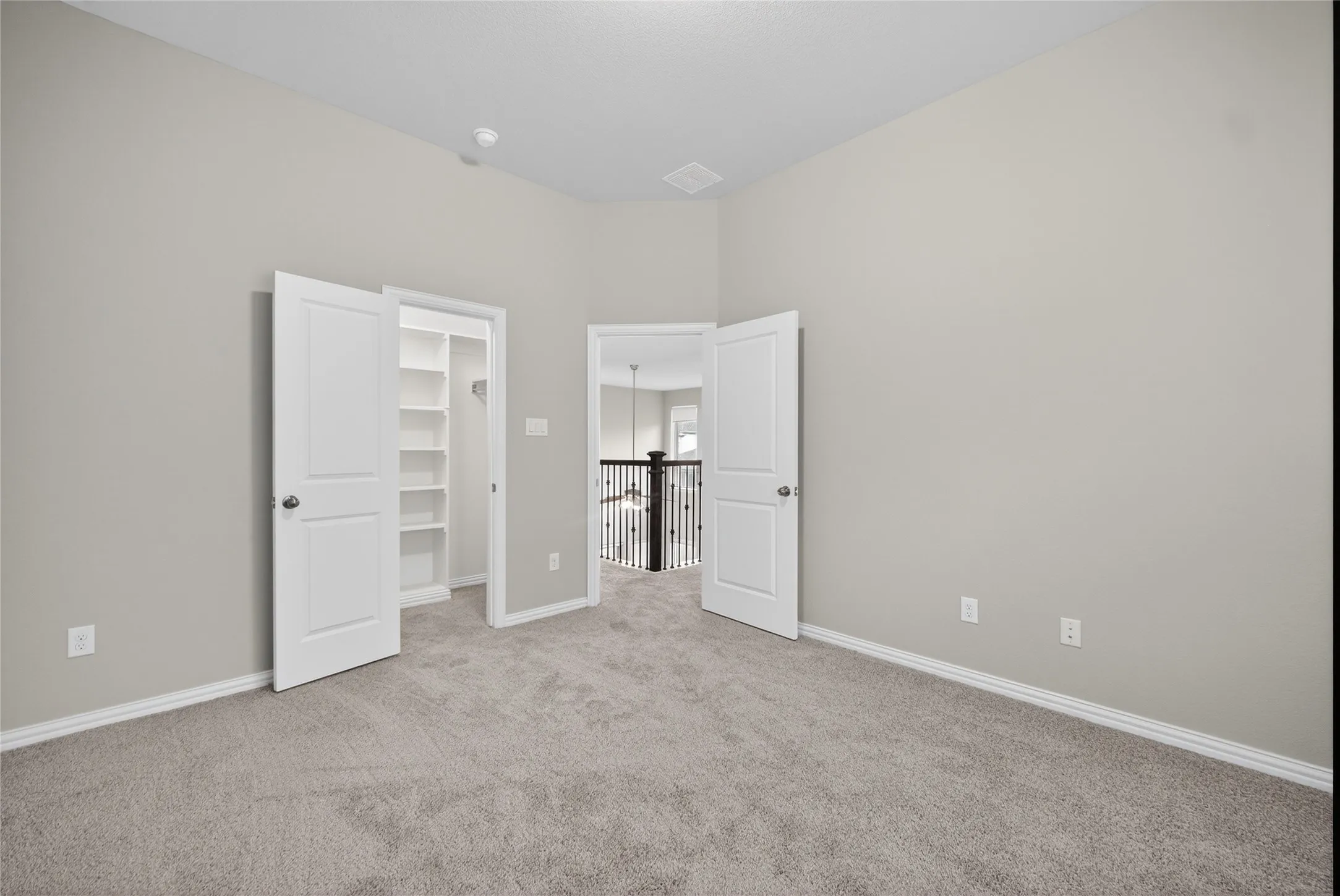 Neutral-toned carpeting, vaulted ceiling, and built-in closet shelving