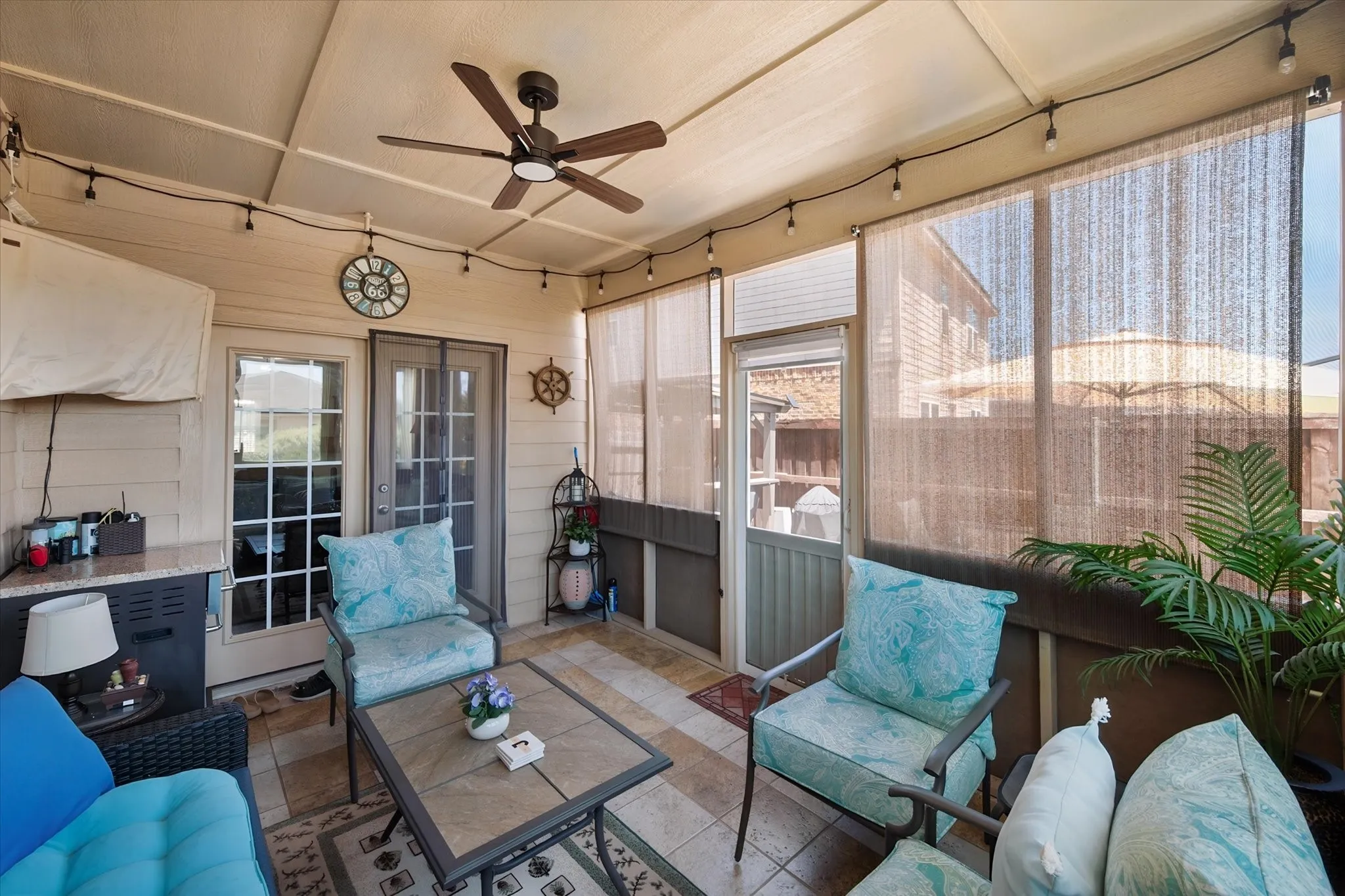 Screened porch featuring a ceiling fan, tiled flooring, wood-finish wall paneling, and multiple glass-paned doors