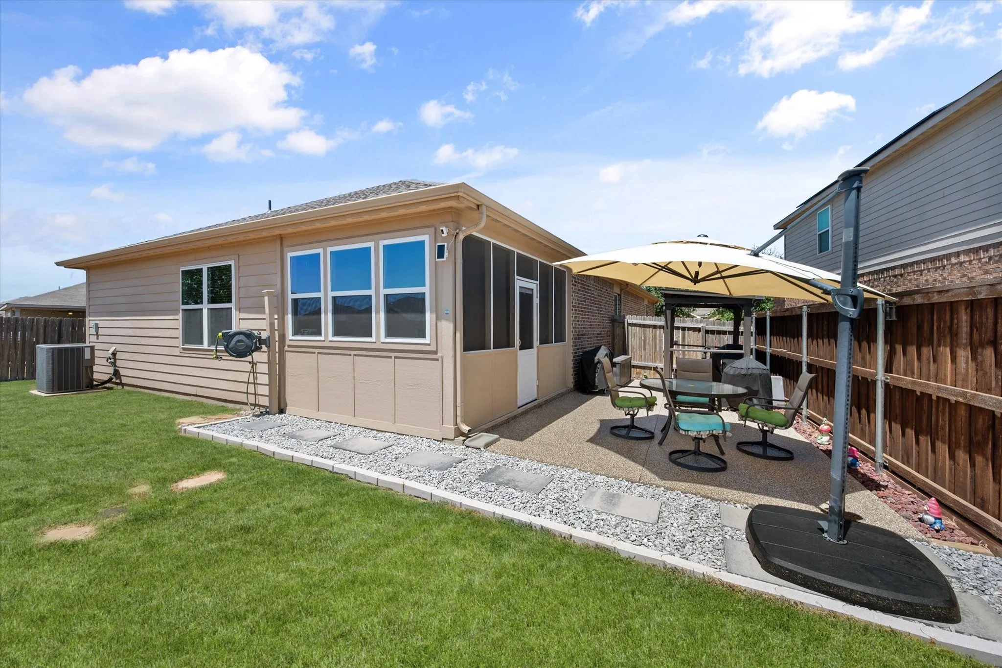 Screened porch with multiple windows, leading to an exterior patio with a gravel border
