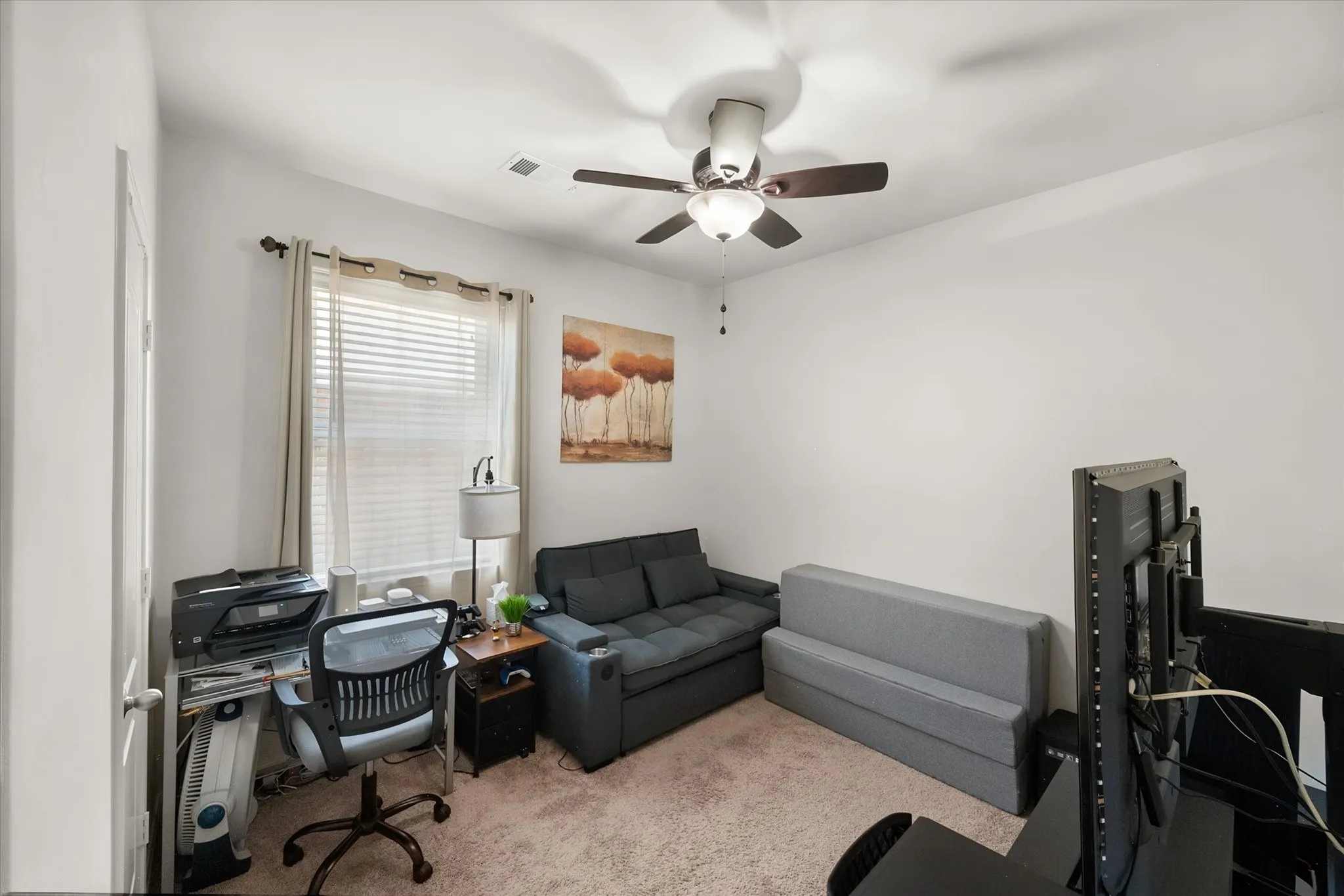 Bedroom used as office,  window with blinds, ceiling fan with integrated lighting, neutral carpet flooring, and white painted walls