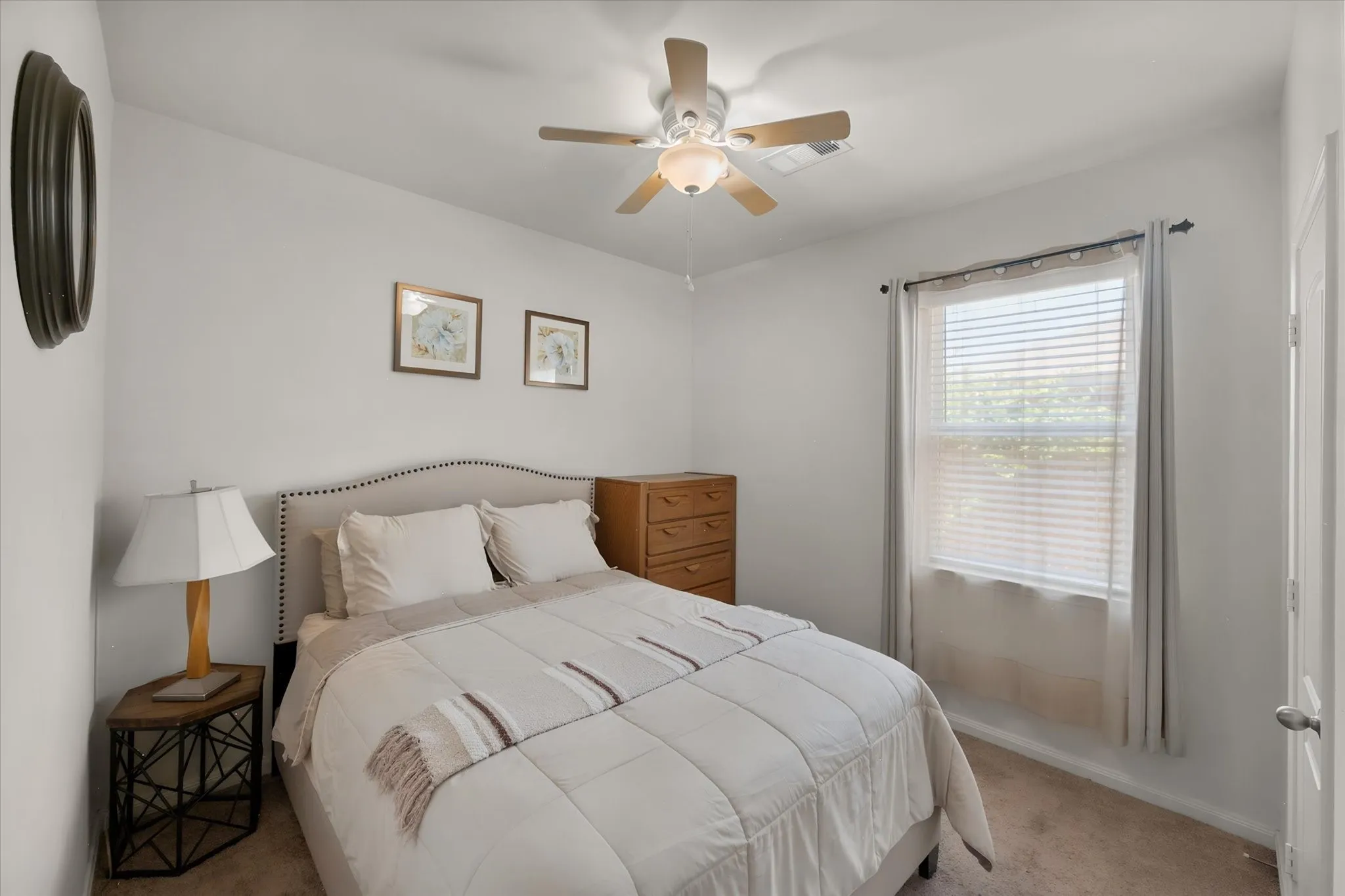 Neutral wall paint, ceiling fan with integrated lighting, window with blinds, and textile curtains