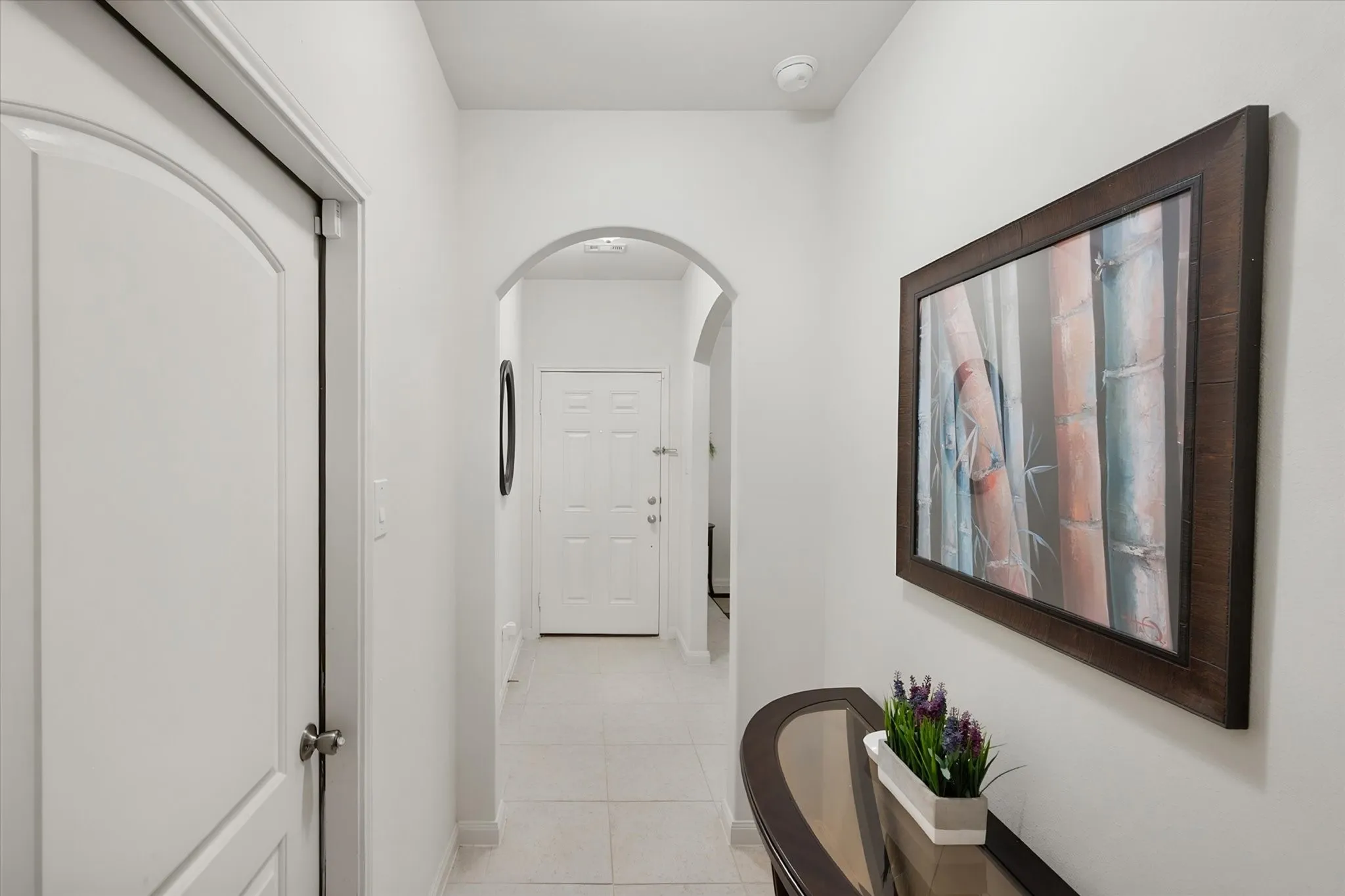 White interior doors with arched top panels, light-toned tile flooring, and arched doorways