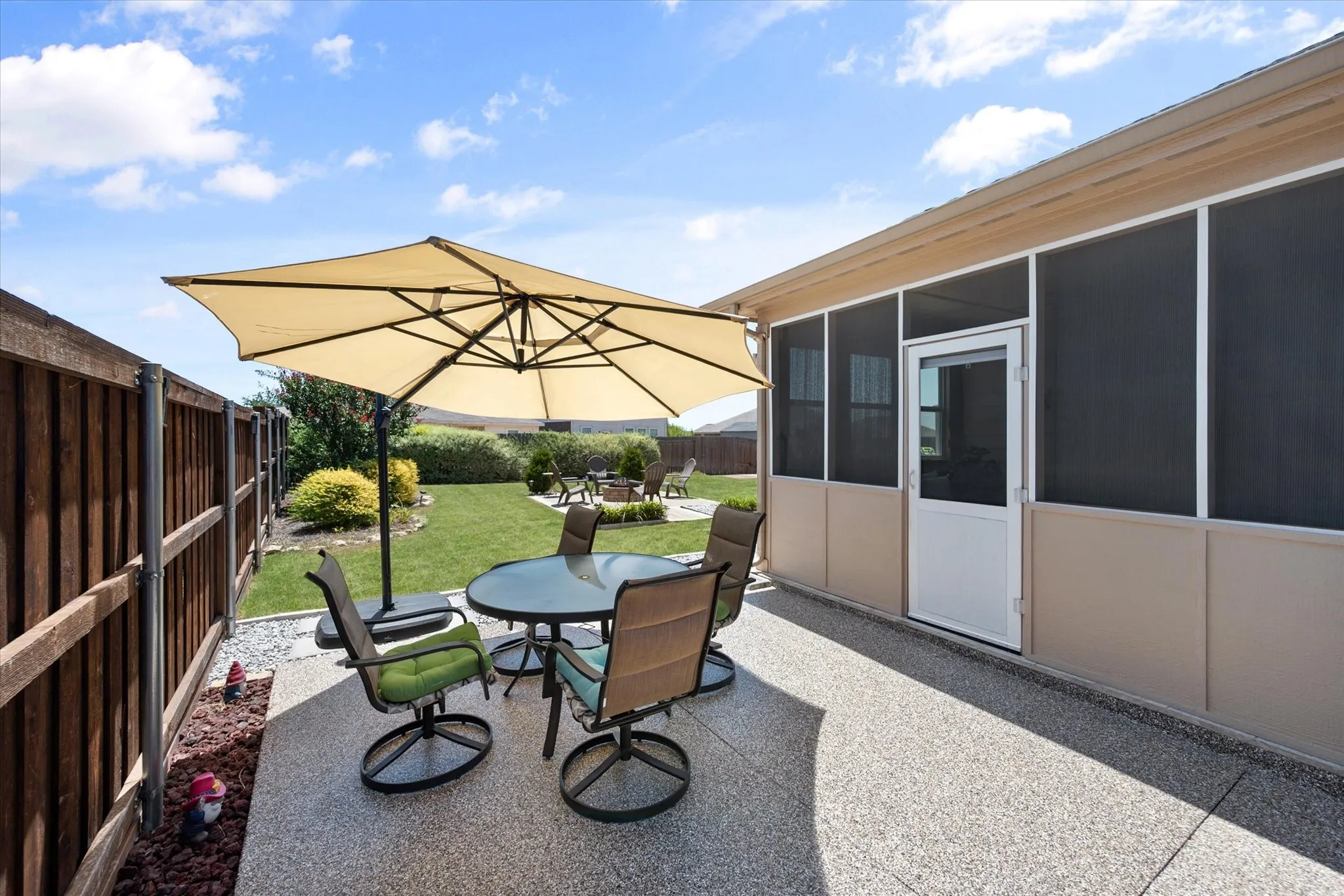 Expansive screened-in porch with a white door, concrete patio, and a manicured lawn