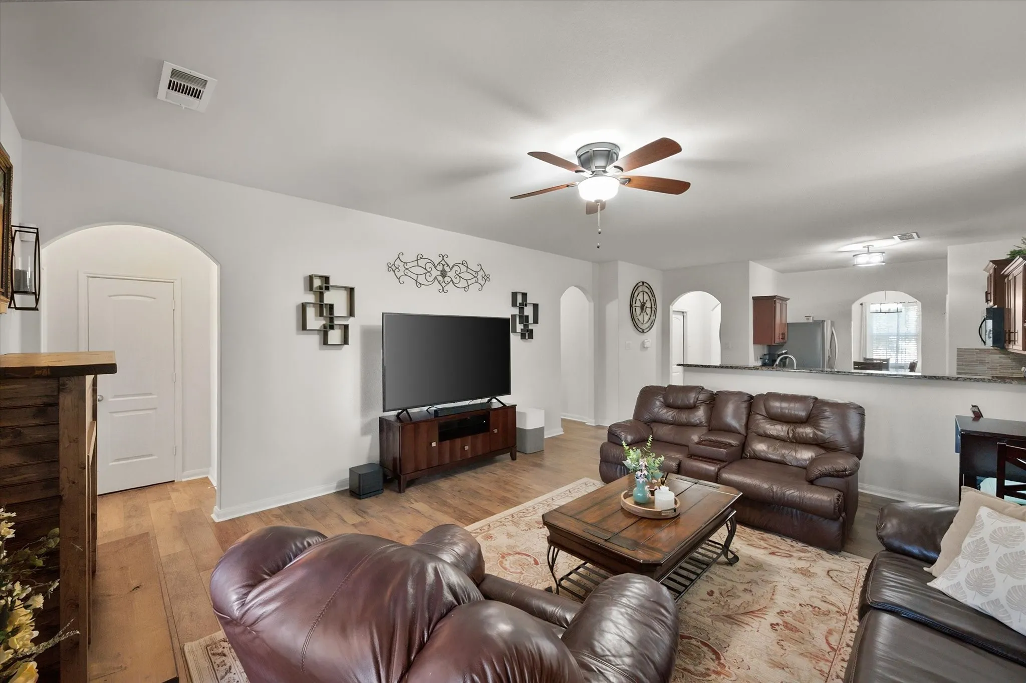 Spacious living area with wood-finish flooring, recessed lighting, and a ceiling fan