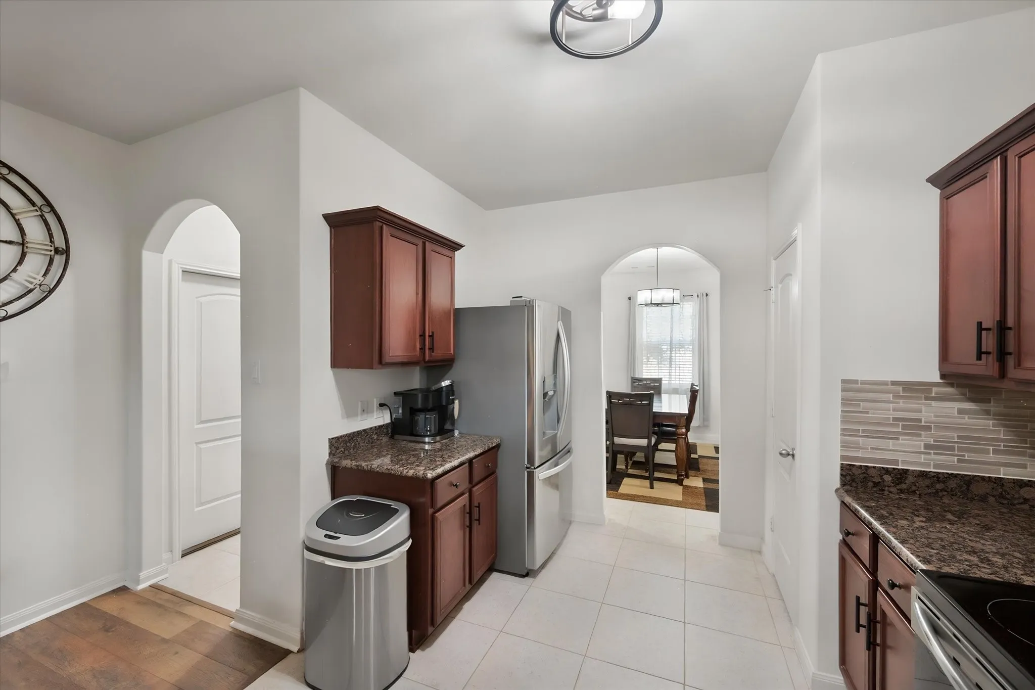 Kitchen featuring wood cabinetry, stainless steel and black appliances, speckled countertops, and a tiled backsplash