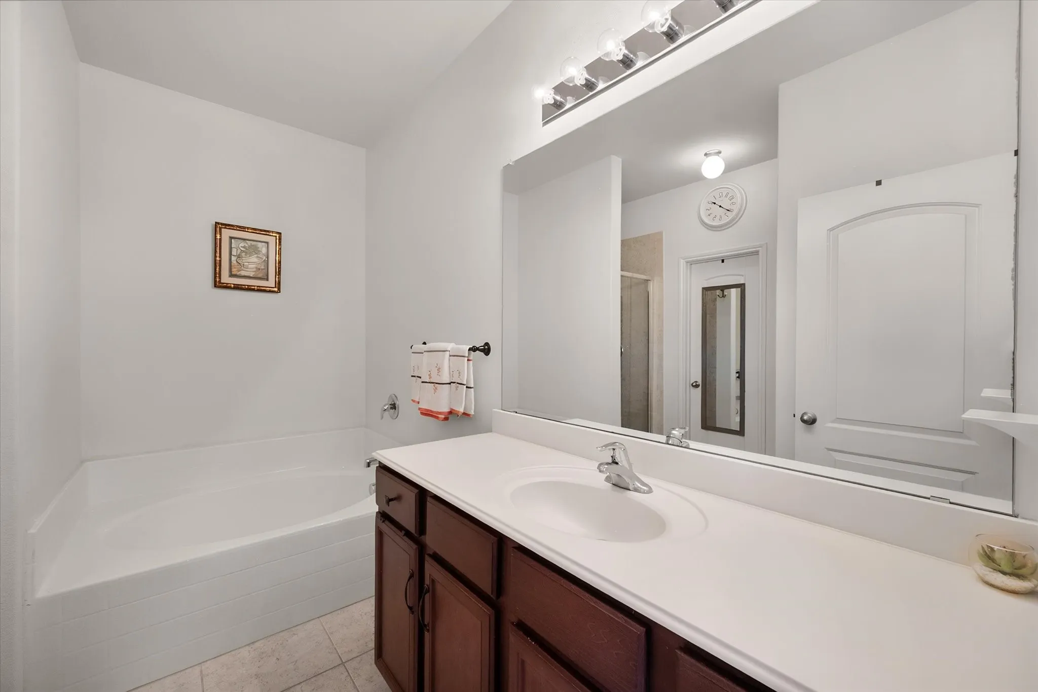 Single basin vanity with wood-finish cabinetry and a white countertop
