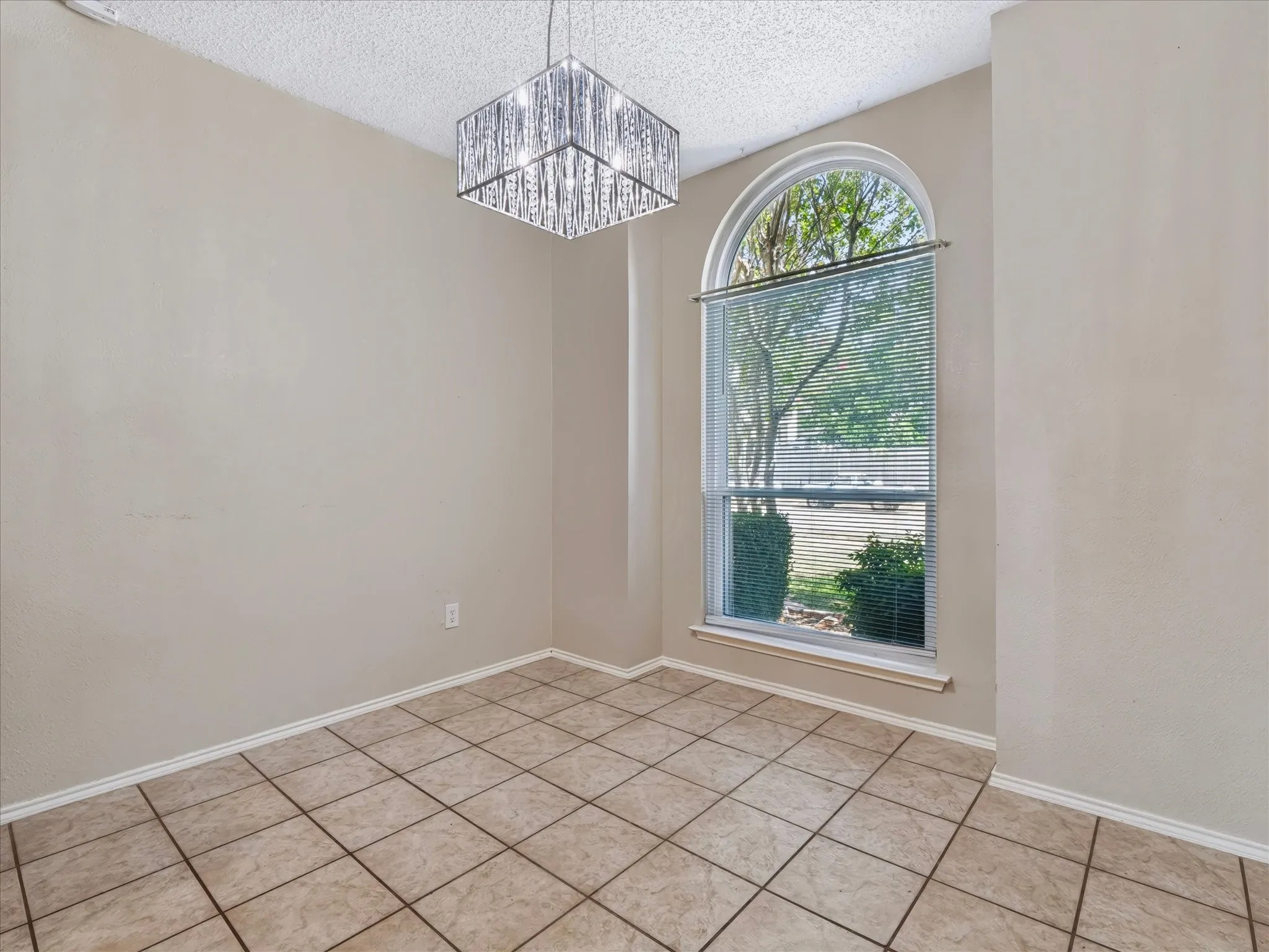 Recessed arch window, crystal chandelier, tile flooring, and neutral wall tones