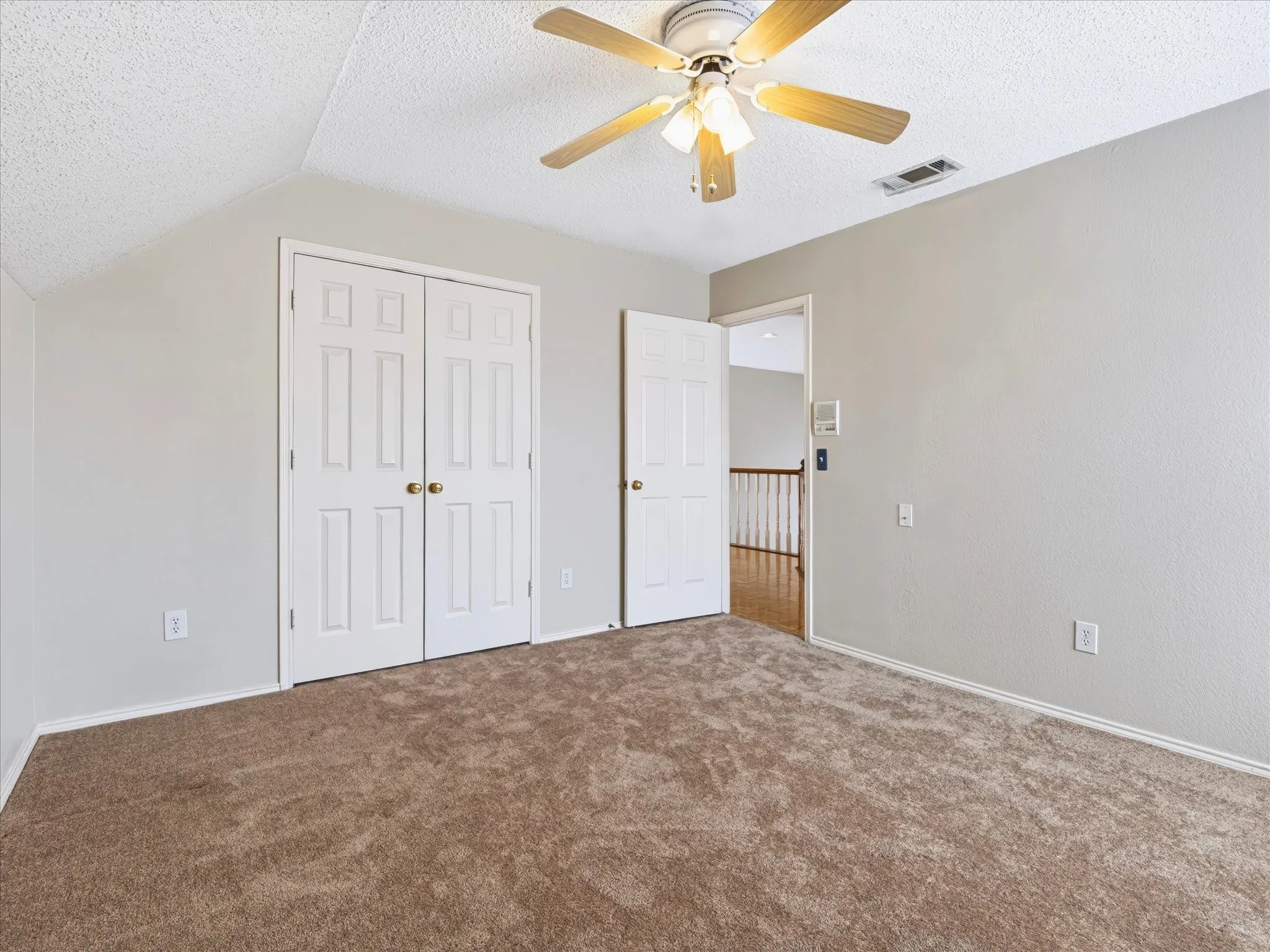 Neutral tone walls, ceiling fan, brown carpet, white paneled doors, and an additional doorway