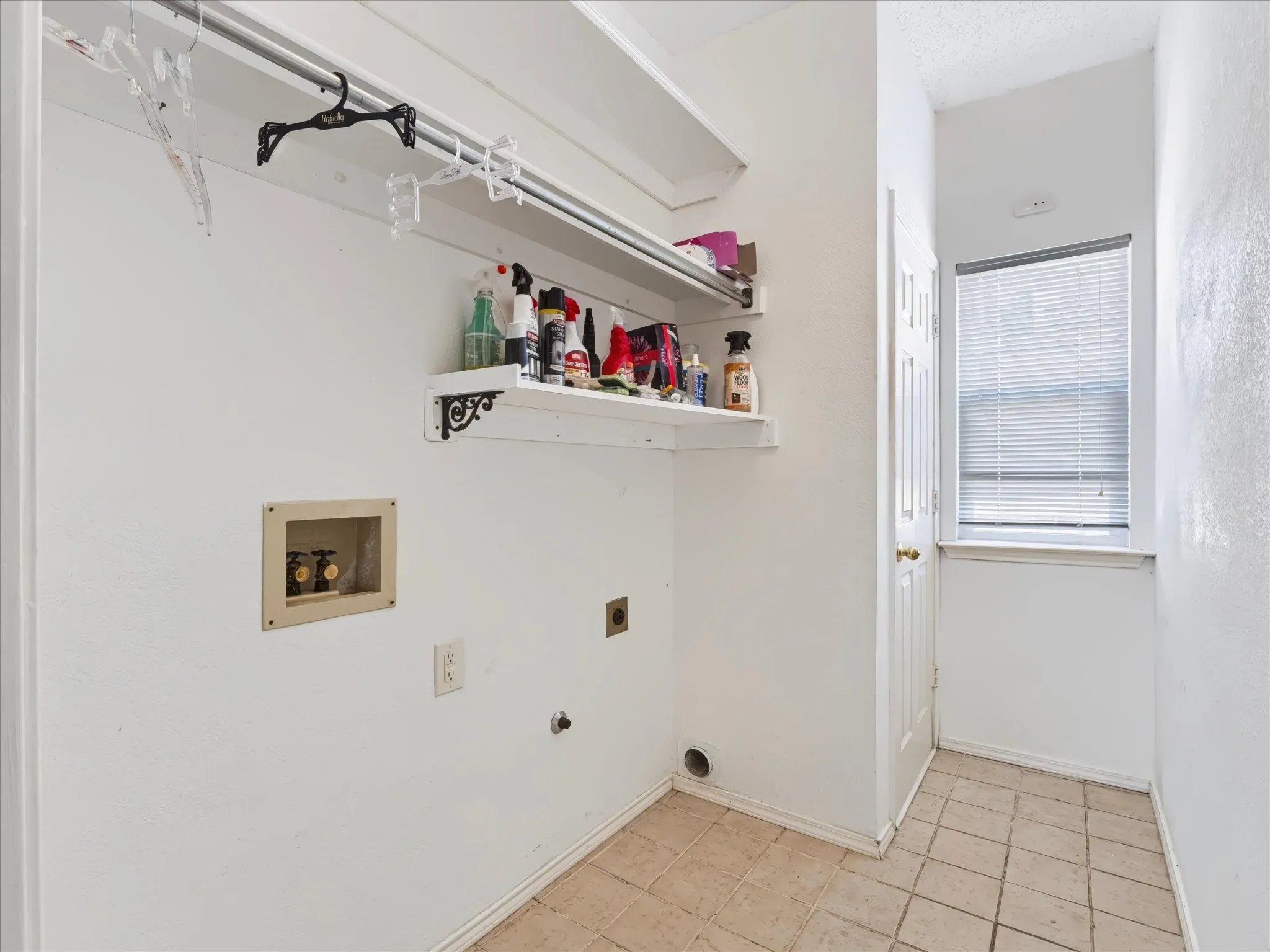 Laundry area with tiled flooring, built-in shelving, and window with blinds