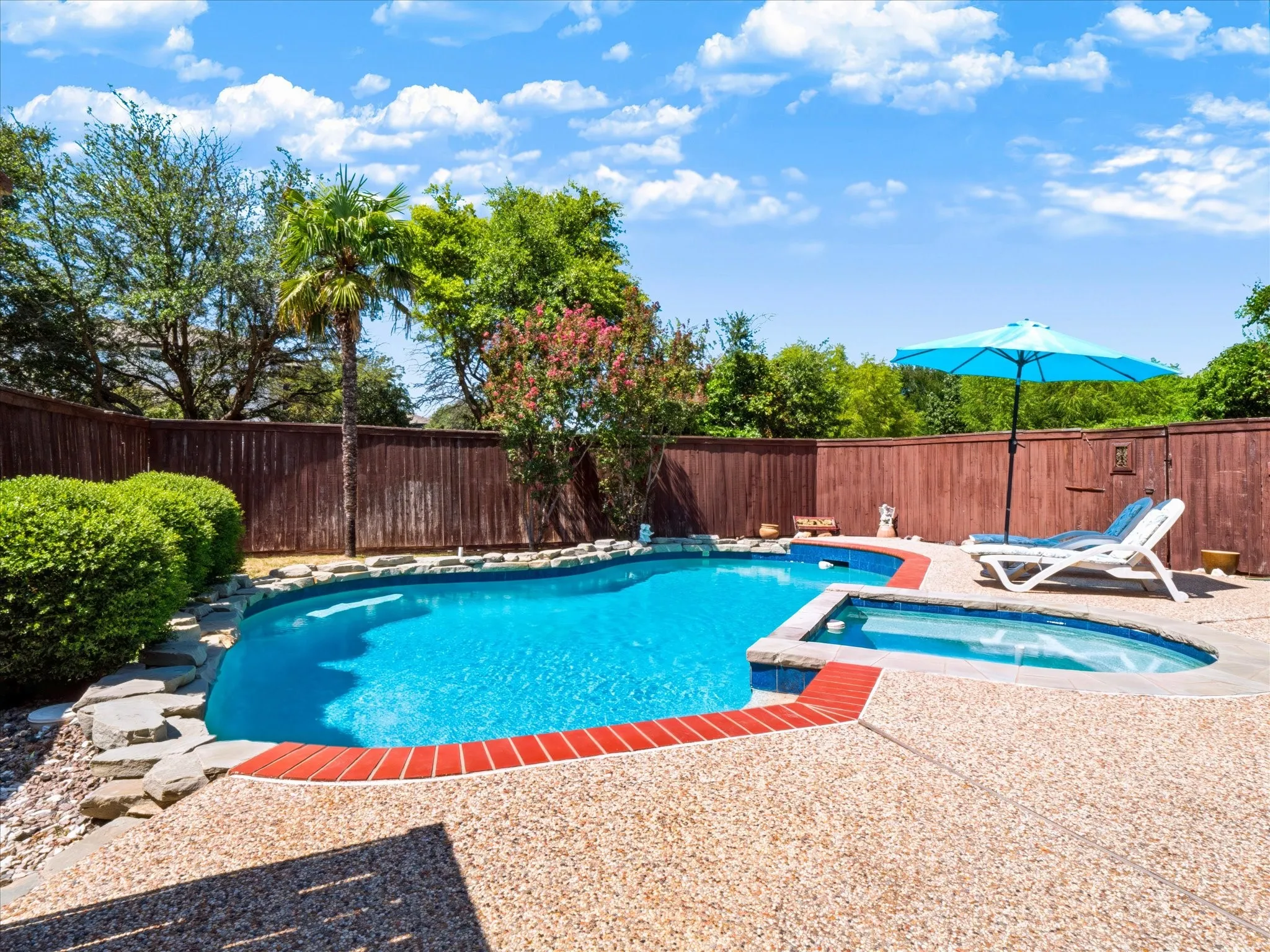 Backyard oasis featuring a swimming pool, integrated spa, and aggregate concrete decking